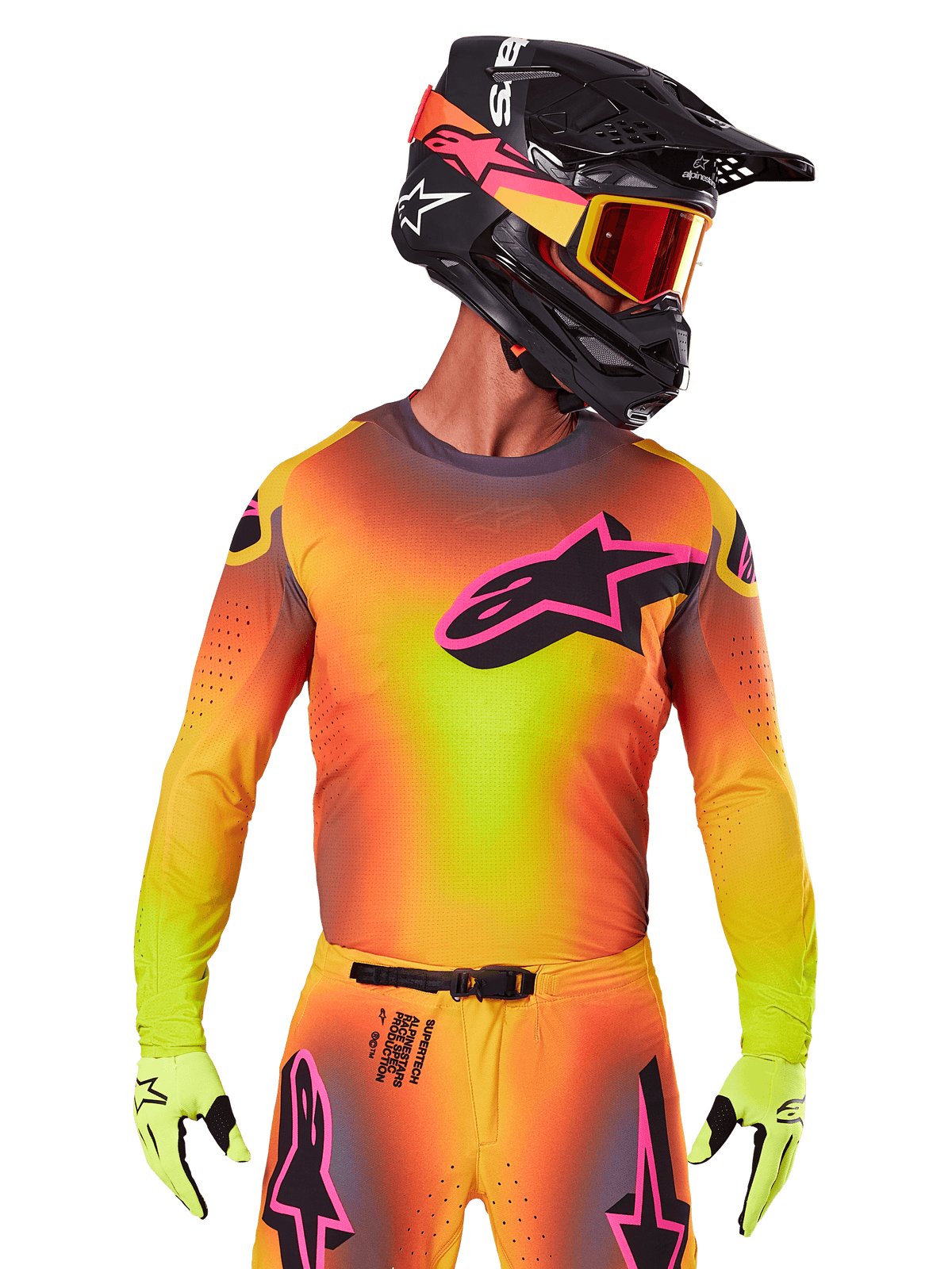 Pilota di motocross con maglia Supertech Lipan 2025, vivace sfumatura gialla, arancione e rosa, grande logo a stella Alpinestars nero con profilo rosa sul petto, perforazioni laser per la ventilazione, vestibilità atletica da gara, abbinata a pantaloni coordinati, guanti gialli e casco nero con maschera.