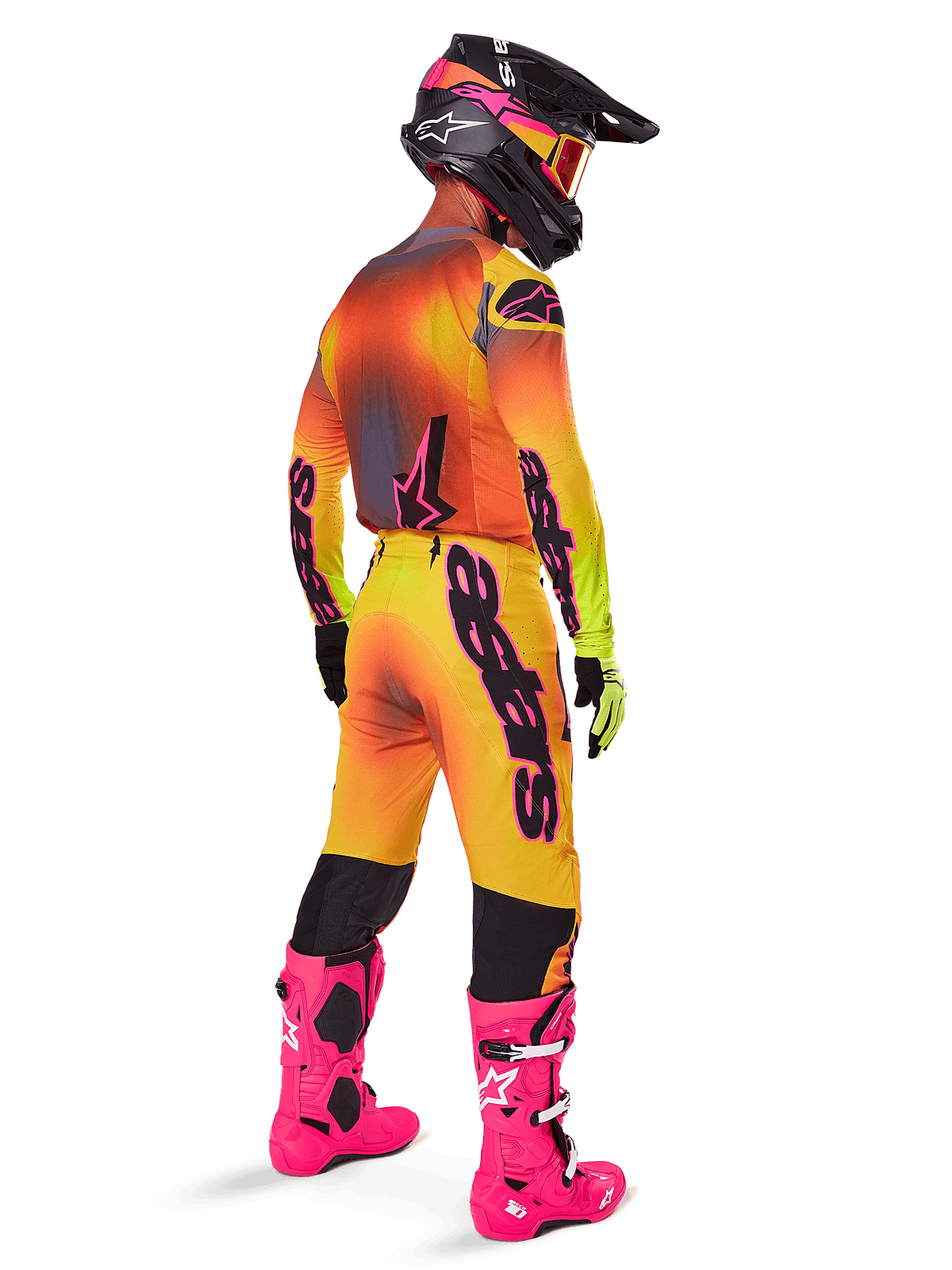 Pilota di motocross visto da dietro che indossa il completo Alpinestars 2025 Supertech Lipan, maglia con sfumatura giallo-arancione e dettagli rosa, pantaloni coordinati, stivali rosa acceso e casco nero con grafiche rosa e gialle, outfit coordinato per gare professionali