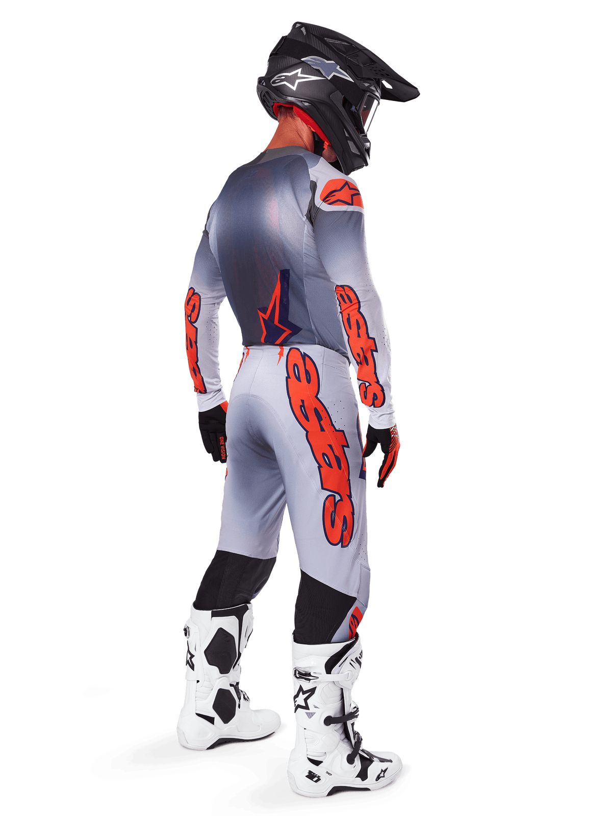 Pilota di motocross visto di profilo posteriore con maglia e pantaloni Alpinestars Supertech Lipan 2025, colori grigio e arancione fluo, logo Alpinestars arancione su maniche e gambe, casco nero e stivali bianchi, completo professionale per gare off-road