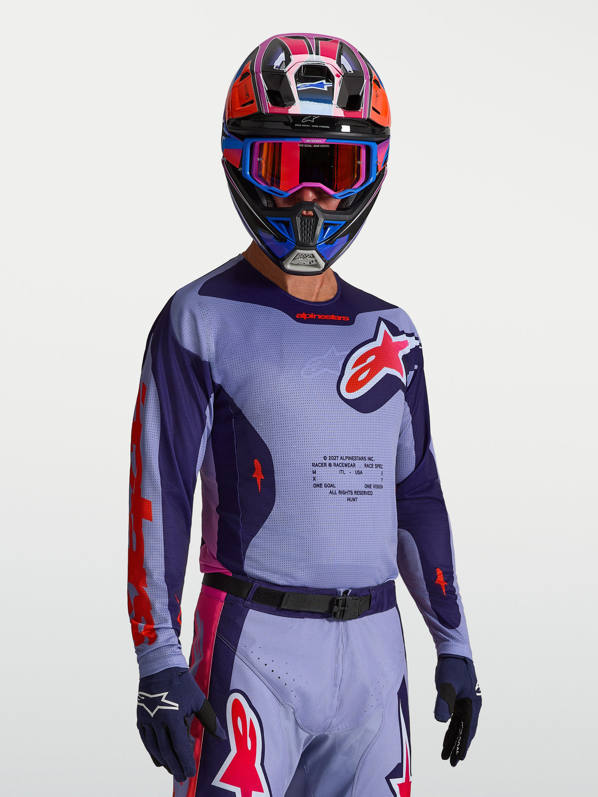 Alpinestars maglia Racer Air Hunt, maglia da motocross ventilata per uomo, viola e rosa, con costruzione in mesh traspirante, indossata con casco e guanti coordinati.