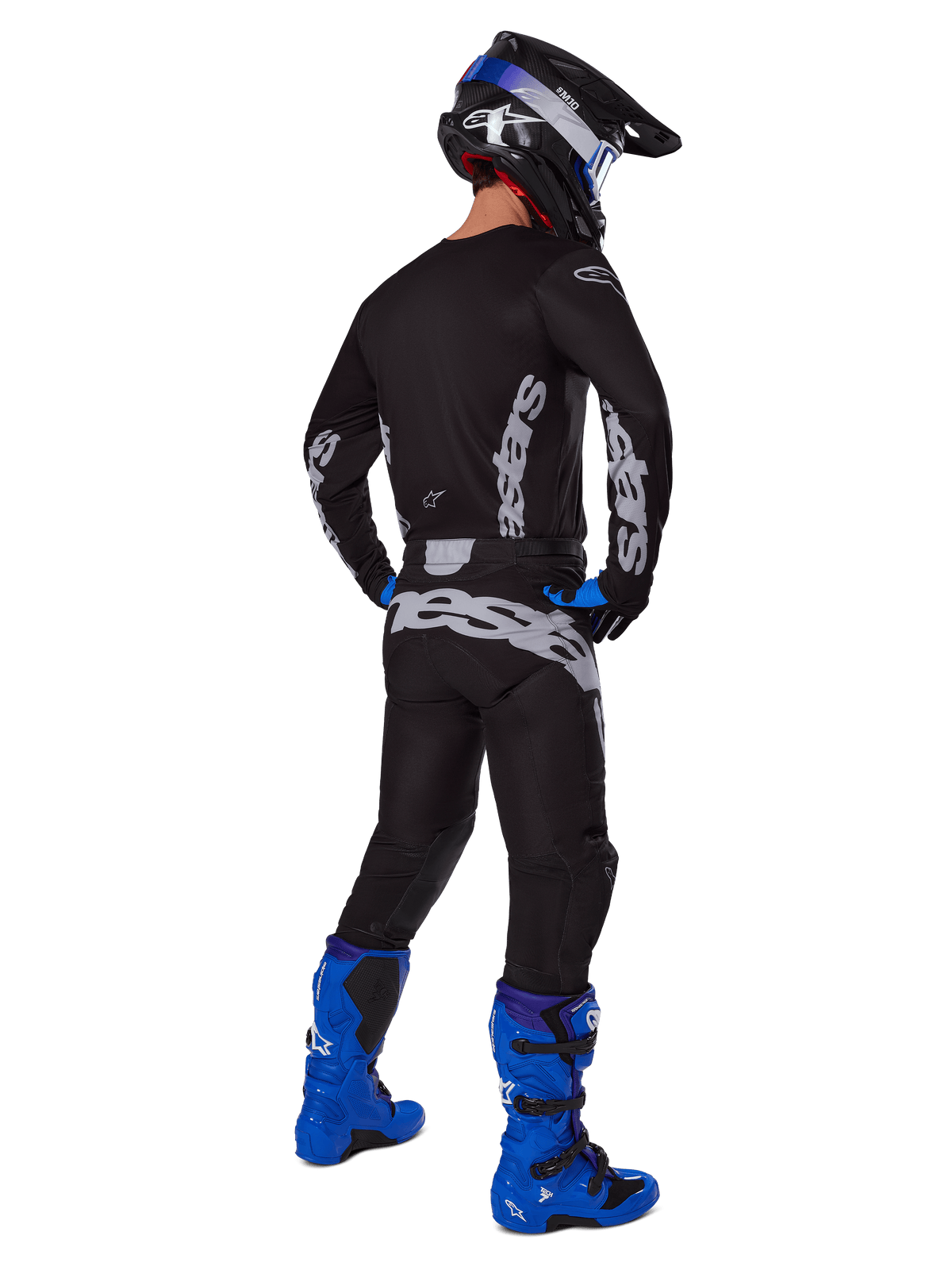 Pilota di motocross visto da dietro che indossa il set Alpinestars 2025 Racer Graphite, maglia e pantaloni nero e grigio con branding grigio, abbinati a stivali da motocross blu acceso, casco nero e blu e guanti blu, abbigliamento completo da fuoristrada ad alte prestazioni.