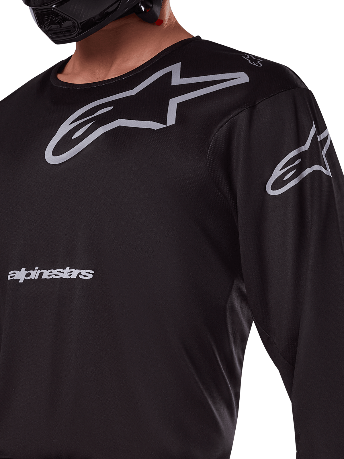 Alpinestars 2025 Racer Graphite Jersey, maglia da motocross nero e grigio, primo piano del pilota con marchio Alpinestars e loghi A-star grigi, materiale in politessuto tecnico per guida fuoristrada