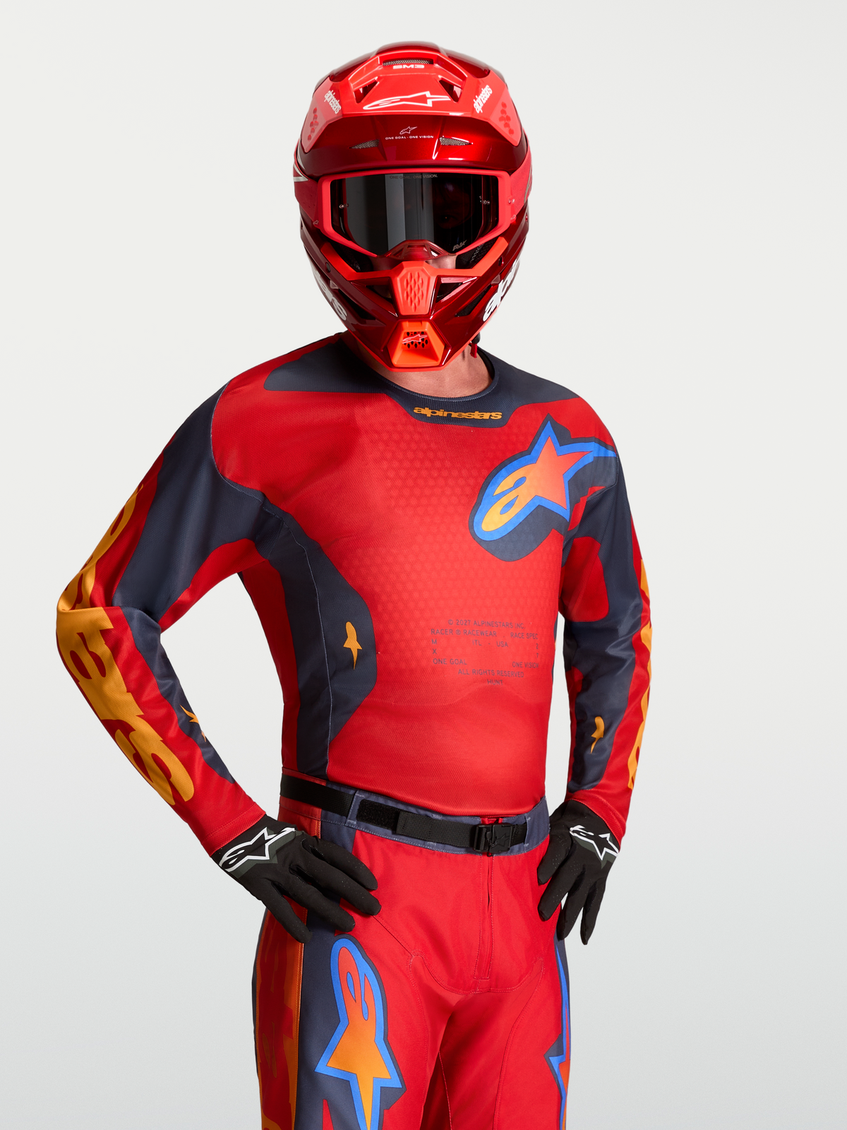 Alpinestars Maglia Racer Hunt, maglia da motocross uomo, rossa e grigia, con inserti in rete traspirante, indossata con casco coordinato, abbigliamento tecnico racing per off-road