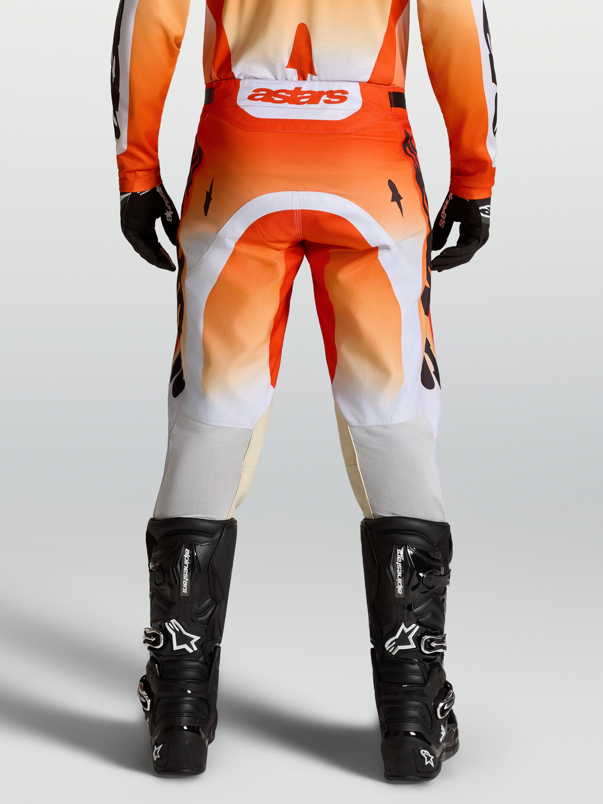 Alpinestars Pantaloni Racer Amber, pantaloni da motocross rossi e bianchi, vista posteriore su modello con stivali neri.