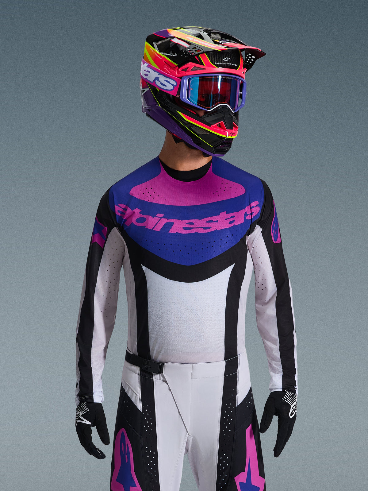 Alpinestars Techstar Knif Jersey 2026, maglia da motocross, nero, grigio chiaro e viola, logo Alpinestars rosa sul petto, indossata con casco colorato e pantaloni da motocross coordinati, vestibilità atletica da gara con perforazioni tagliate al laser per la ventilazione