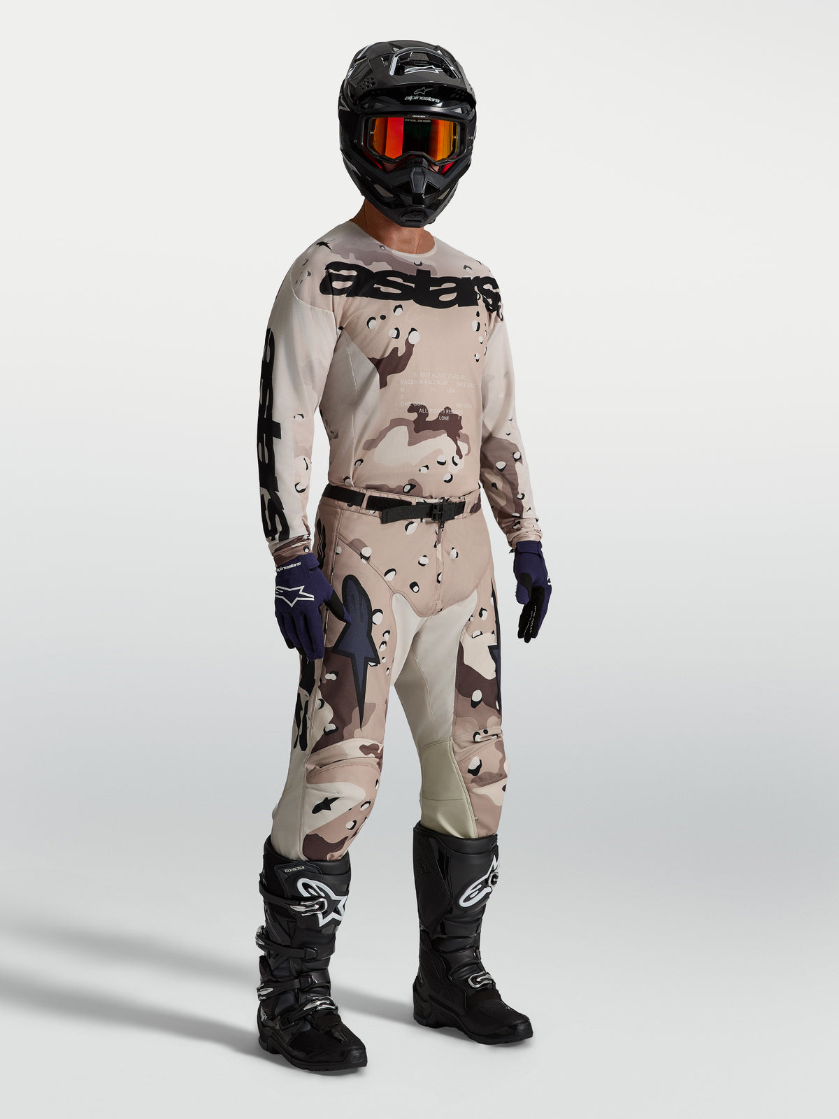 Alpinestars Maglia Racer Lone, maglia da motocross da uomo, desert camo e nero, costruzione leggera e traspirante in tessuto polifibra, indossata con equipaggiamento completo da fuoristrada.