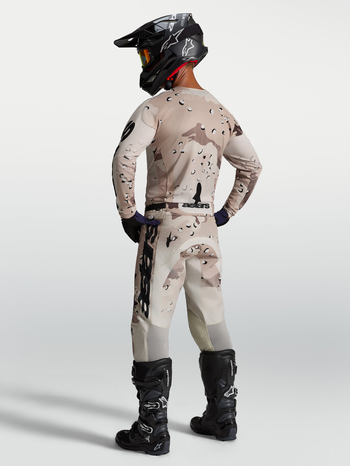 Alpinestars Maglia Racer Lone, maglia da motocross da uomo, mimetico desert e nero, vista posteriore con casco e stivali.