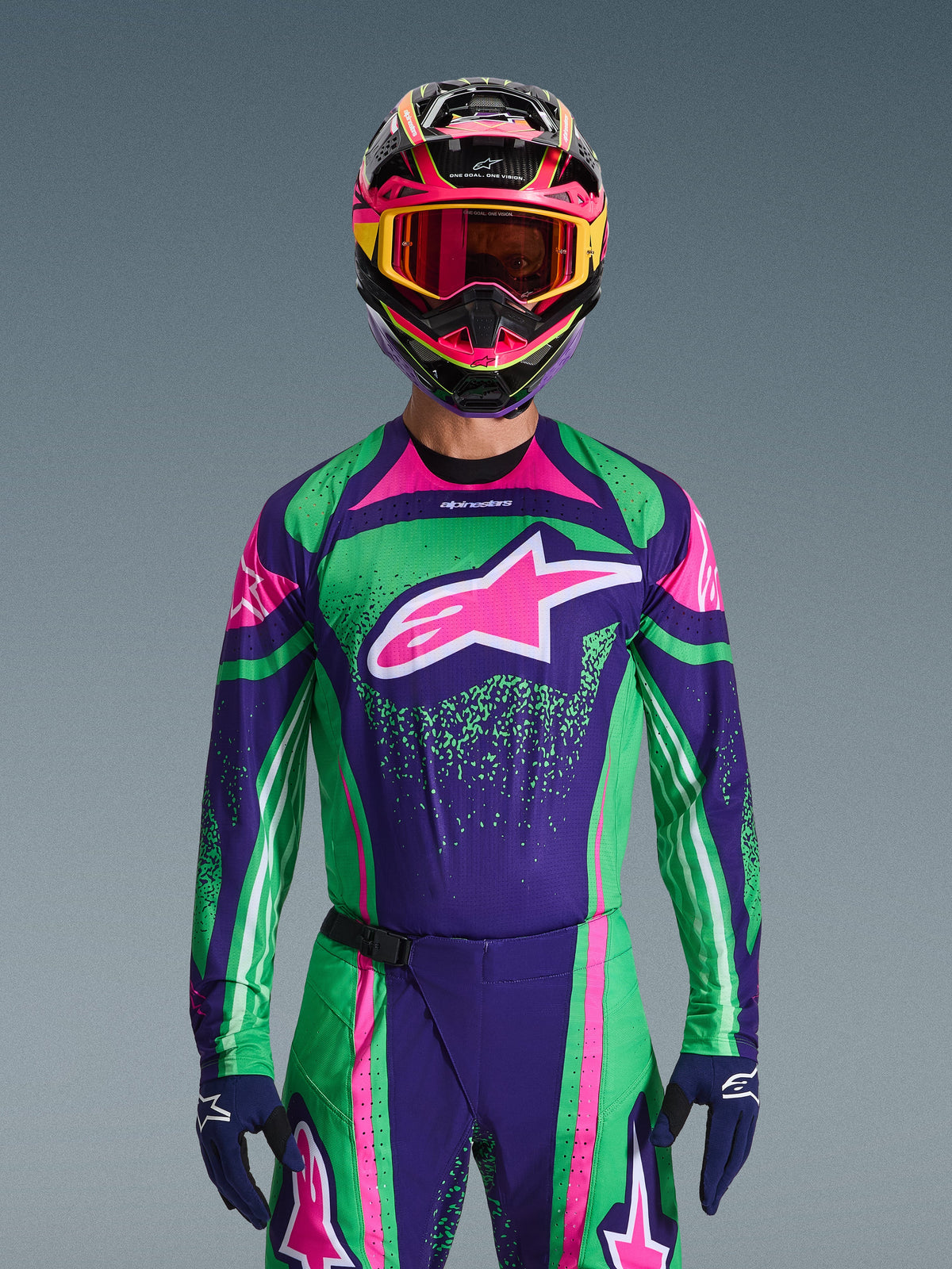 Alpinestars 2026 Techstar Nomur Gear Set, pilota di motocross con maglia da gara verde vivace e viola con accenti rosa, completo coordinato con casco e maschera multicolore, abbigliamento da moto fuoristrada ad alte prestazioni