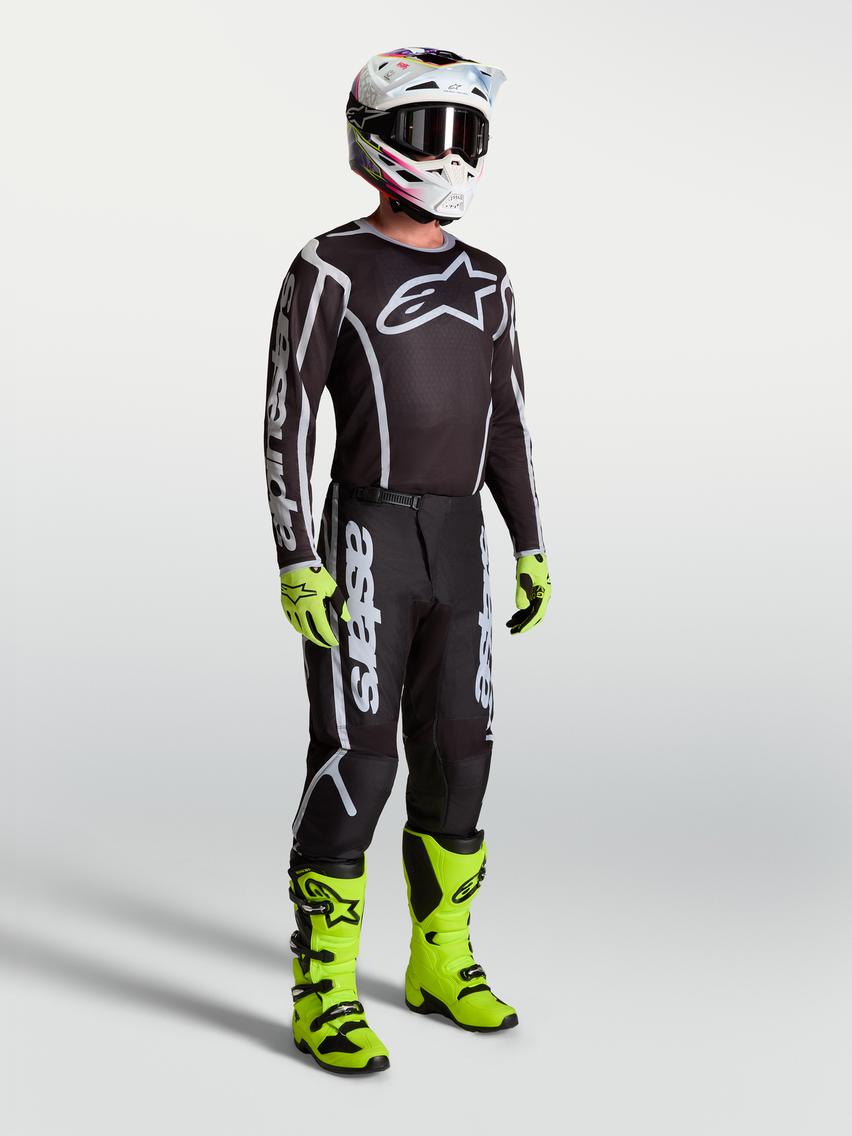 Alpinestars Maglia Fluid Apex V2, maglia da motocross da uomo, nera e argento, indossata con guanti e stivali giallo neon, abbigliamento tecnico per prestazioni off-road