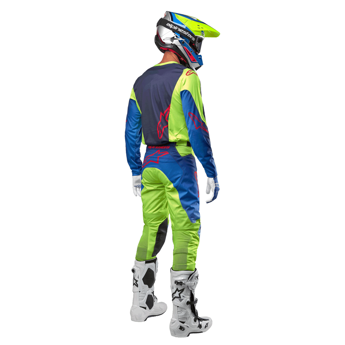Pilota di motocross visto da dietro con maglia Alpinestars Racer Hoen 2024 in Giallo Fluo e Blu Night Navy, pantaloni da motocross abbinati e stivali bianchi, mostra il design posteriore con loghi rossi, completo coordinato per gare off-road professionali