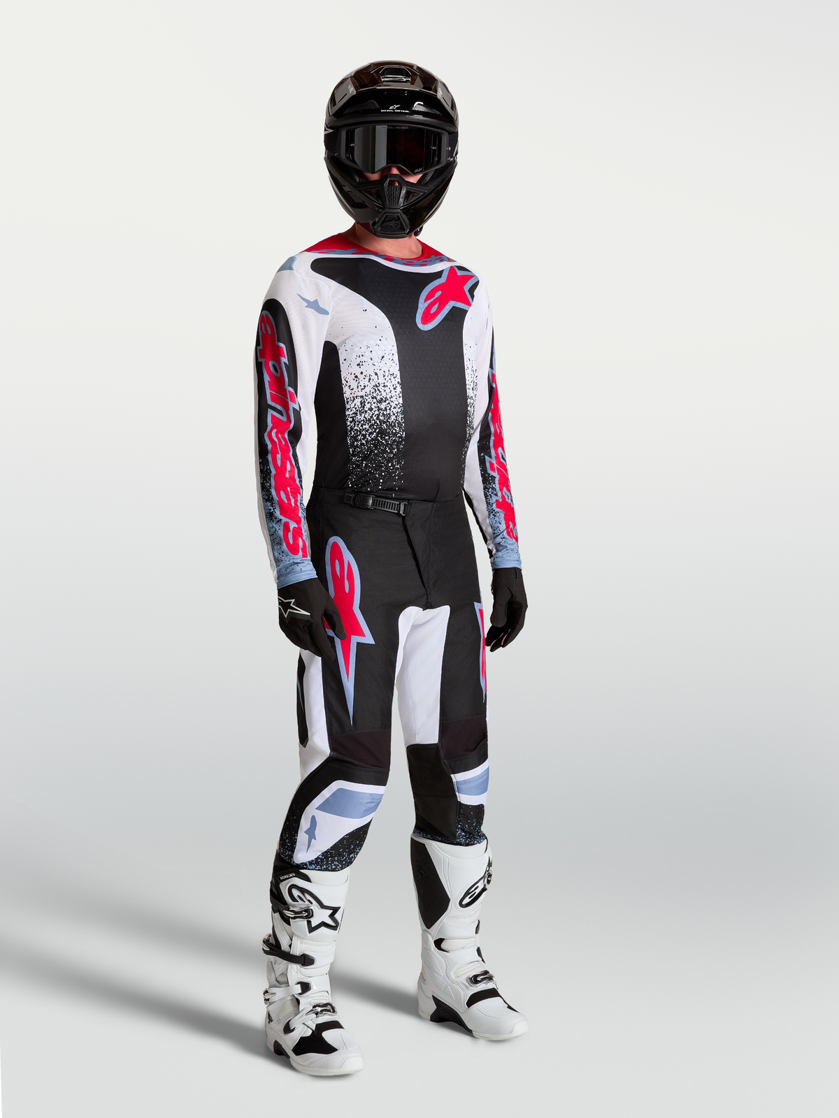 Alpinestars Maglia Fluid Drag, maglia da motocross da uomo, nero, bianco e rosso fluo, in tessuto tecnico traspirante, indossata da un modello con equipaggiamento completo da off-road