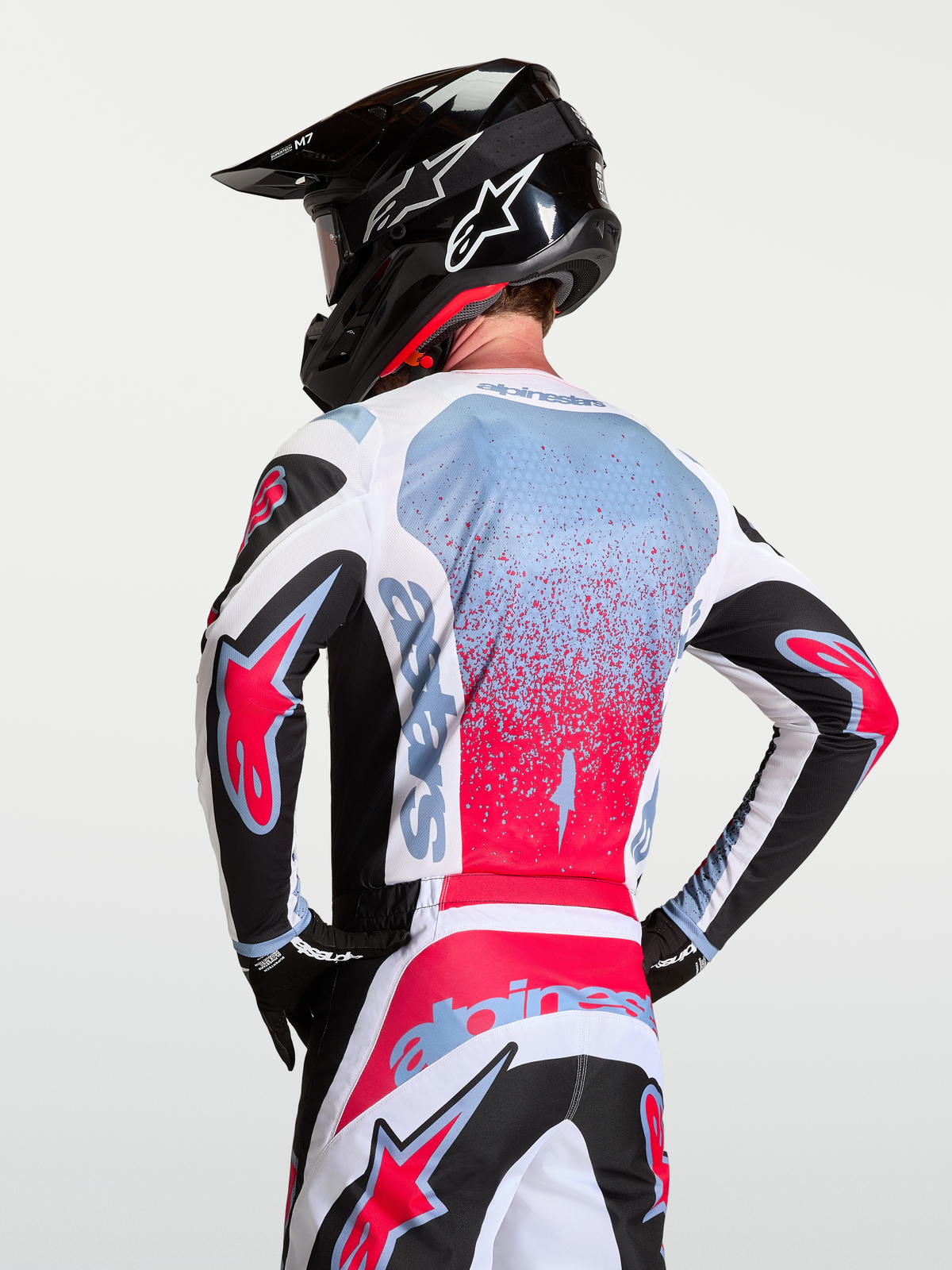 Alpinestars Maglia Fluid Drag, maglia da motocross da uomo, bianco e rosso con accenti nero e blu, indossata da un pilota con casco, poliestere traspirante assorbe l'umidità per off-road