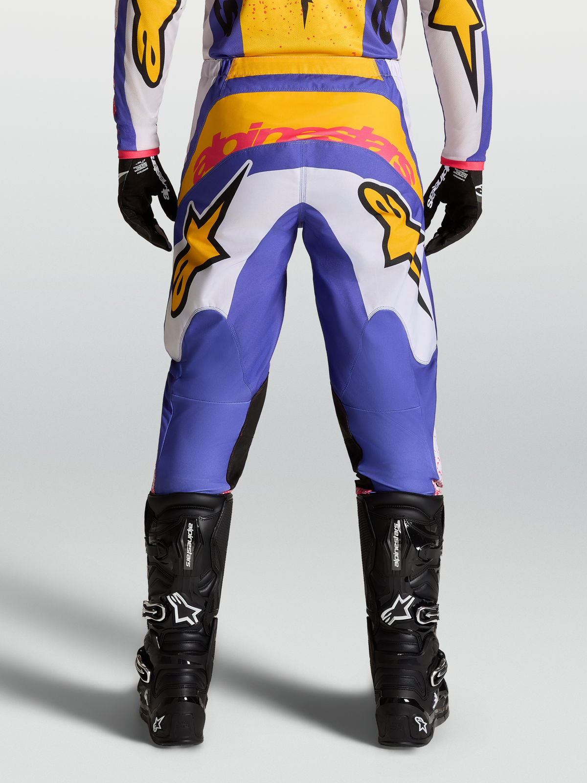 Alpinestars Pantaloni Fluid Drag, pantaloni da motocross blu e oro, vista posteriore, con pannelli elasticizzati e seduta rinforzata, abbinati a stivali tecnici neri