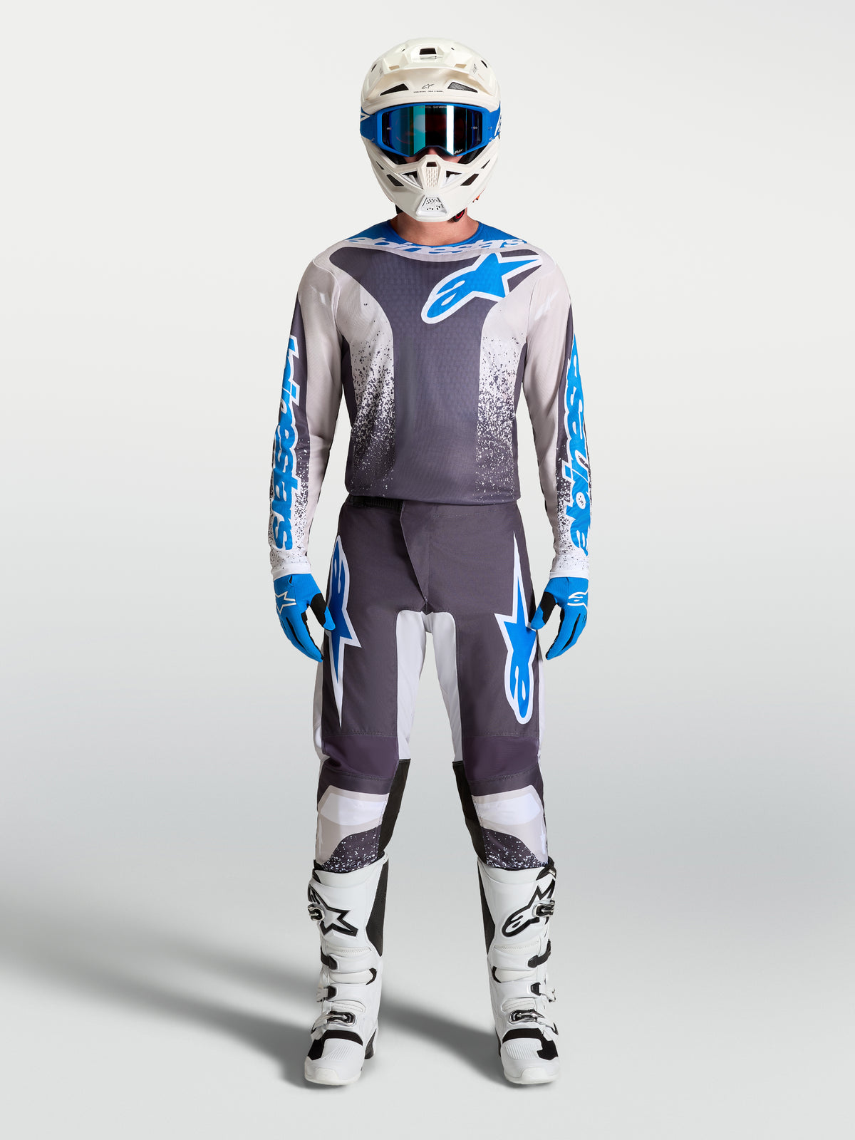 Maglia Alpinestars Fluid Drag grigia e blu, kit da motocross con casco e stivali racing bianchi coordinati.