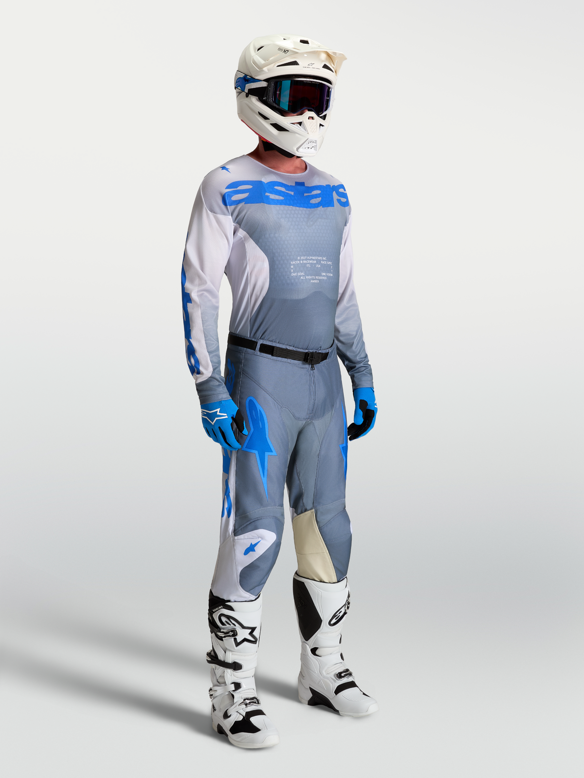 Alpinestars Maglia Racer Amber, maglia da motocross grigia e blu per uomo, indossata da un modello con casco e stivali bianchi.