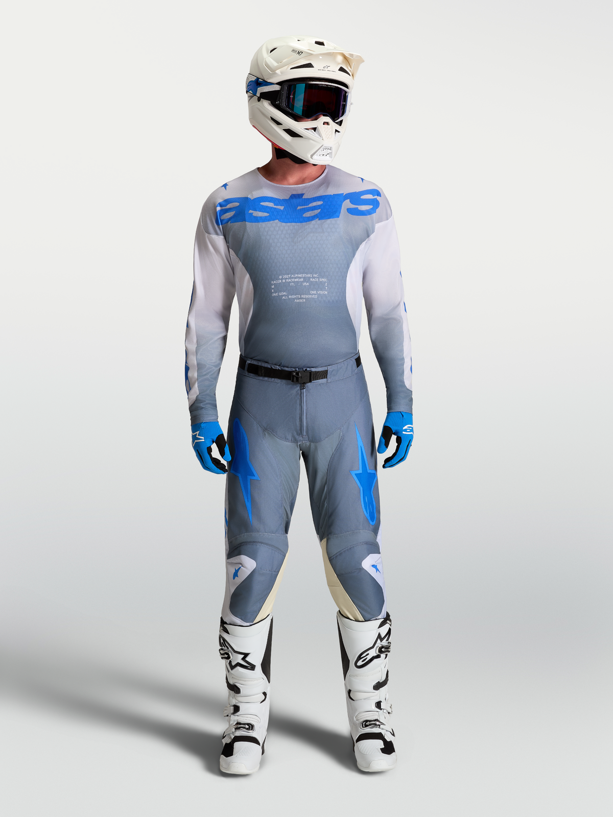Alpinestars Pantaloni e Maglia Racer Amber, completo motocross da uomo, grigio e blu, indossato con stivali e casco bianchi, ideale per guida fuoristrada e motocross, materiali tecnici traspiranti.