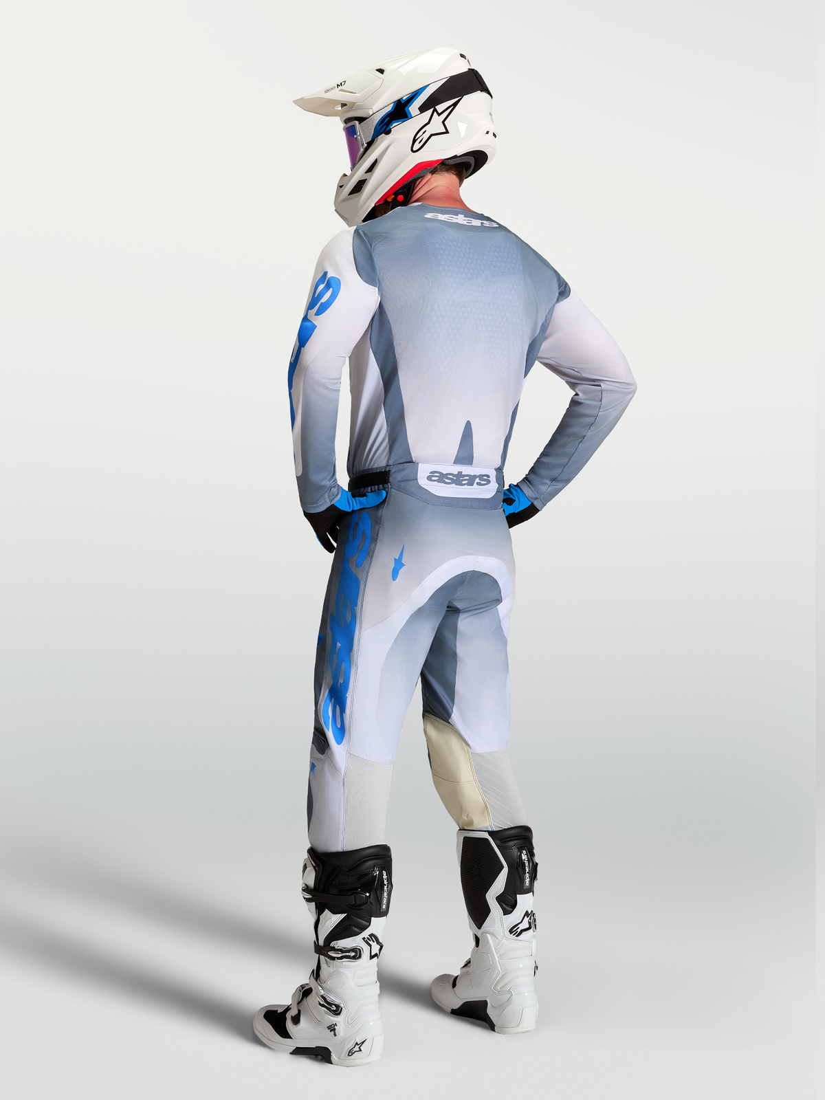 Alpinestars Pantaloni Racer Amber e Gear Set 2027, abbigliamento da motocross uomo, grigio e blu, vista posteriore su pilota.
