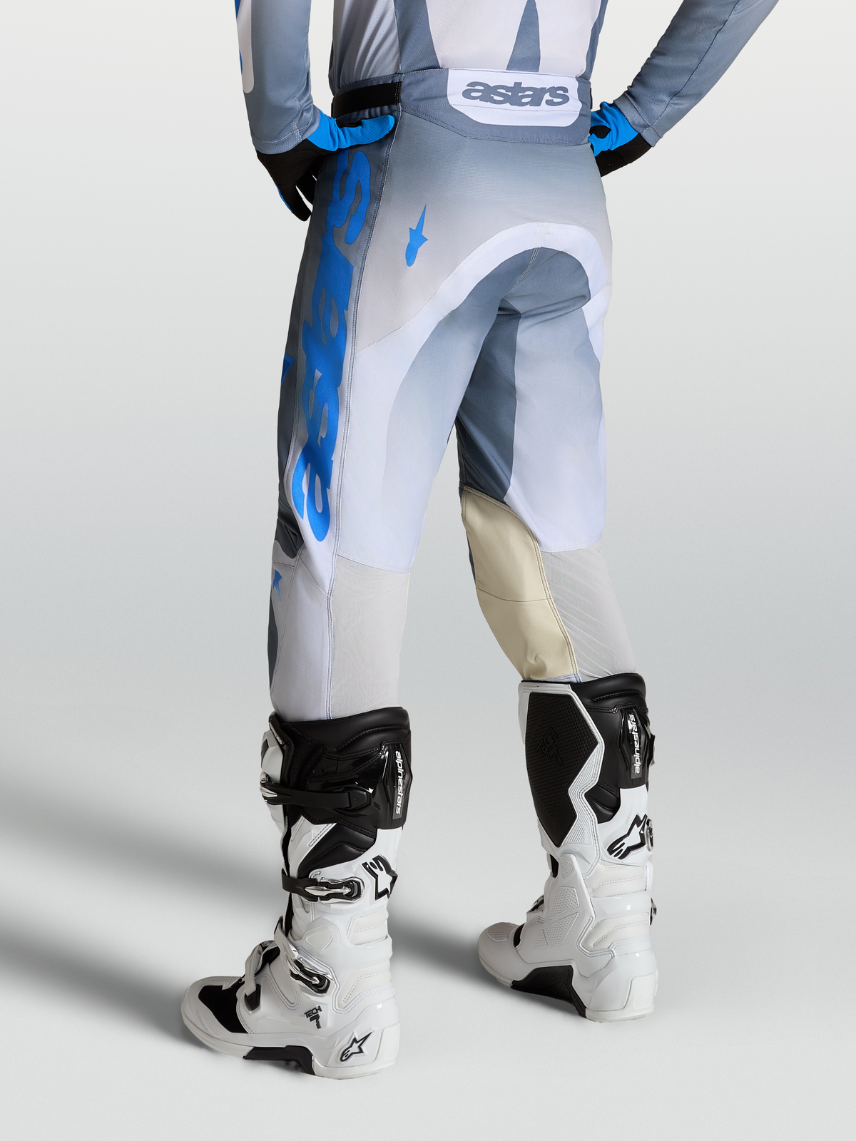 Alpinestars Pantaloni Racer Amber, pantaloni motocross da uomo, grigio e blu, con pannelli interni al ginocchio in pelle e ventilazione posteriore, indossati con stivali Tech 7