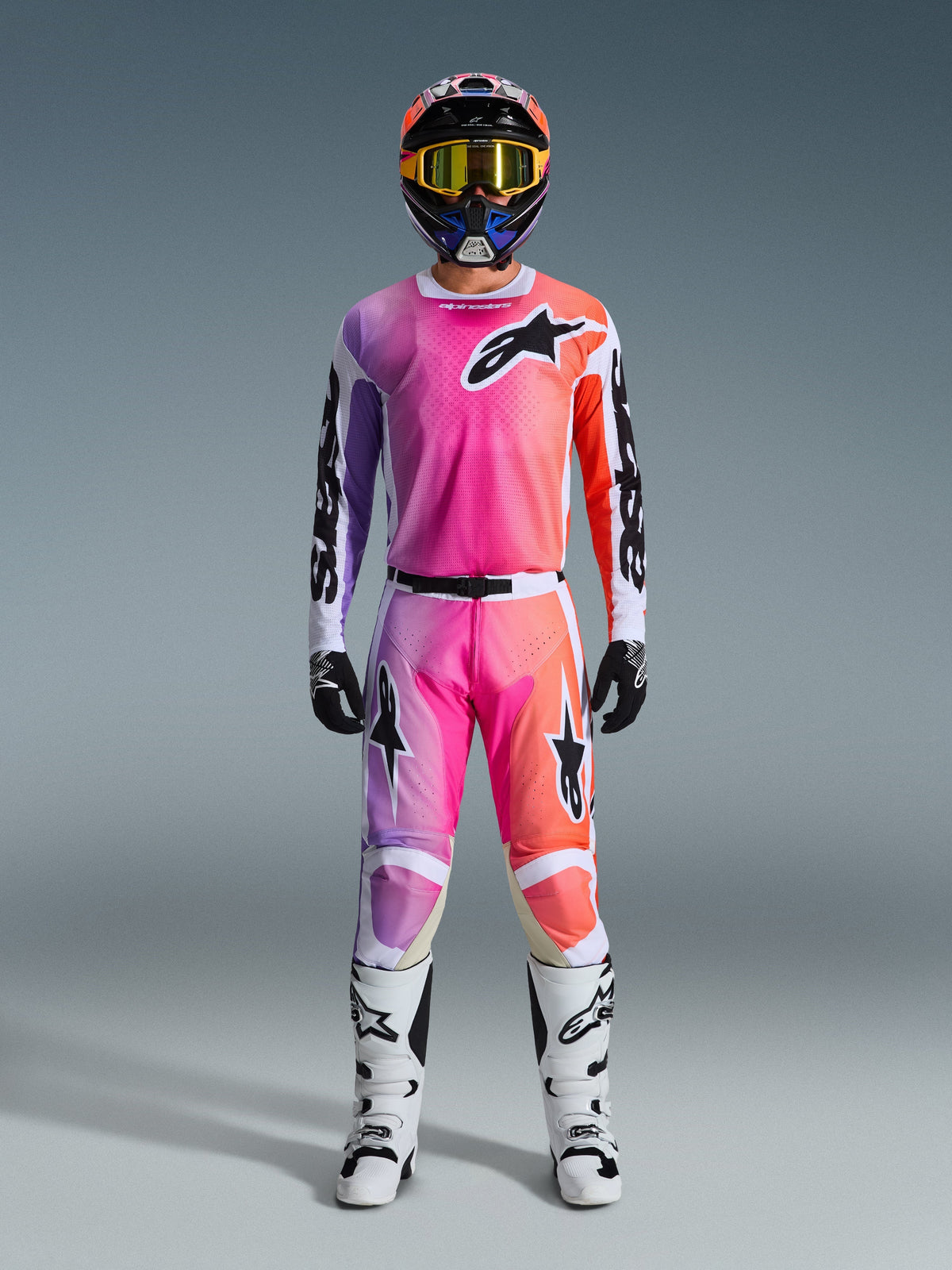 Abbigliamento completo da motocross Alpinestars 2026 Racer Air Portl, maglia e pantaloni con design sfumato rosa, viola e arancione, casco coordinato con maschera gialla, stivali bianchi e guanti neri per un look off-road coordinato