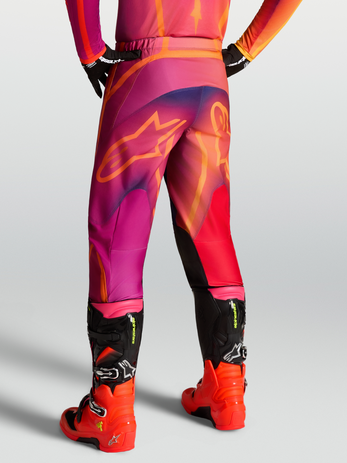 Alpinestars Pantaloni Fluid Kepler, pantaloni motocross da uomo, viola e arancione, design pre-curvato in poliestere 600D, indossati con stivali Tech 7