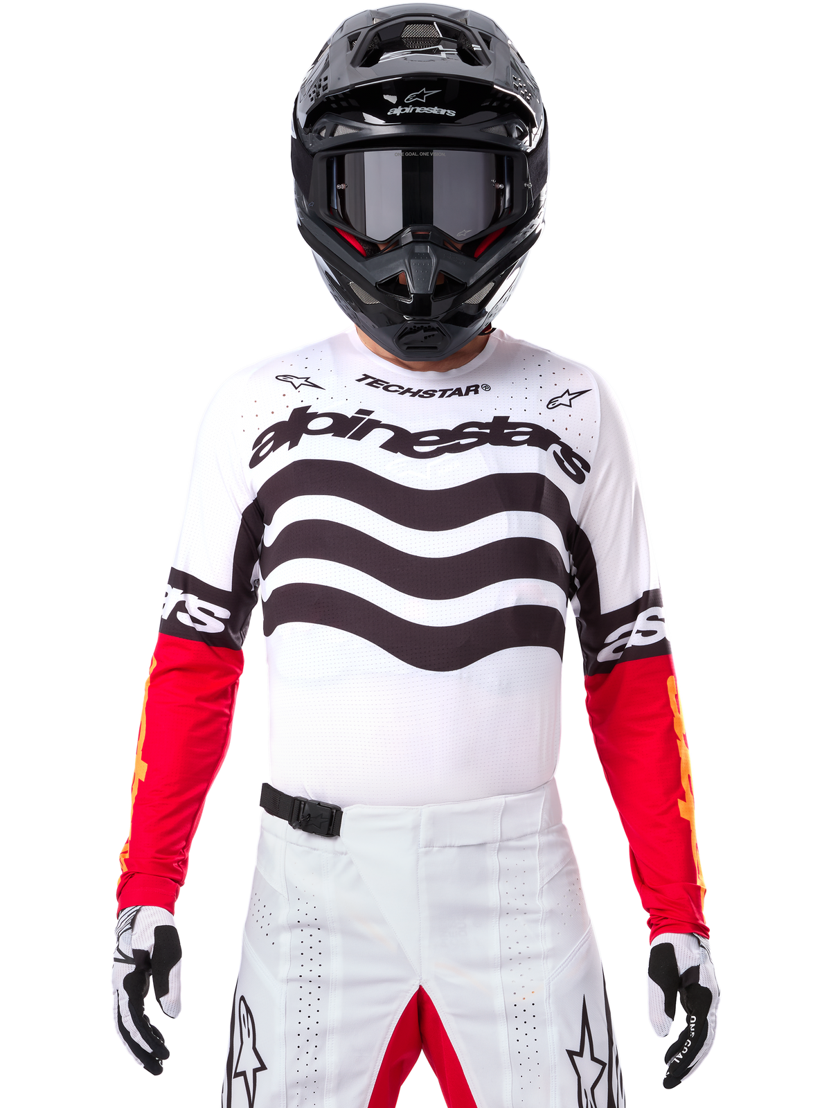 Pilota di motocross con abbigliamento completo da gara, maglia Limited Edition Techstar Deep bianca e nera con maniche rosse, grafiche ondulate e marchio Alpinestars, pantaloni bianchi, casco e maschera neri, outfit coordinato per corse off-road
