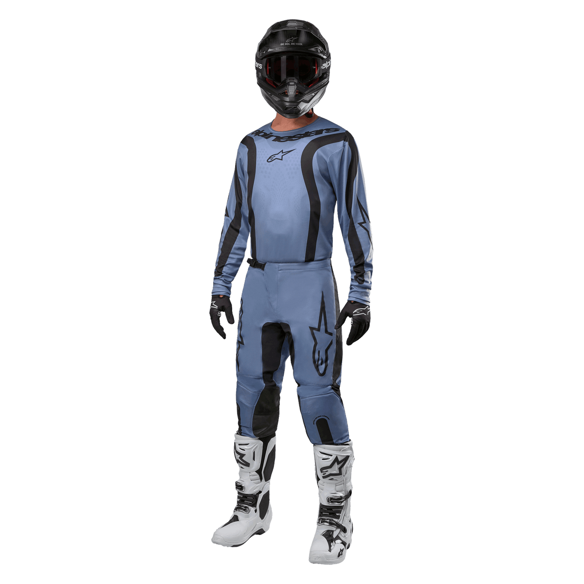 Pilota di motocross con abbigliamento completo da gara, maglia Alpinestars Fluid Lurv 2024 in azzurro e nero, pantaloni coordinati azzurri con inserti neri, stivali bianchi e neri, guanti neri e casco nero con maschera, outfit coordinato per gare fuoristrada
