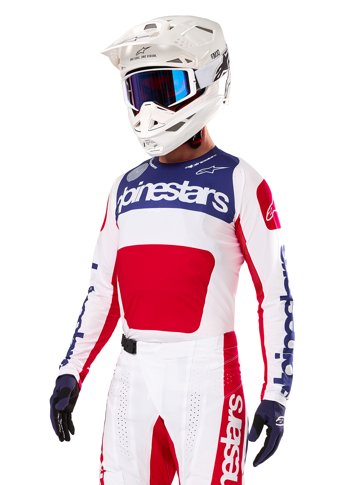 Pilota di motocross con maglia Alpinestars Limited Edition Techstar Fortitude, rosso acceso, bianco e blu, con casco bianco, occhiali blu e pantaloni coordinati, abbigliamento da gara ad alte prestazioni per competizioni off-road