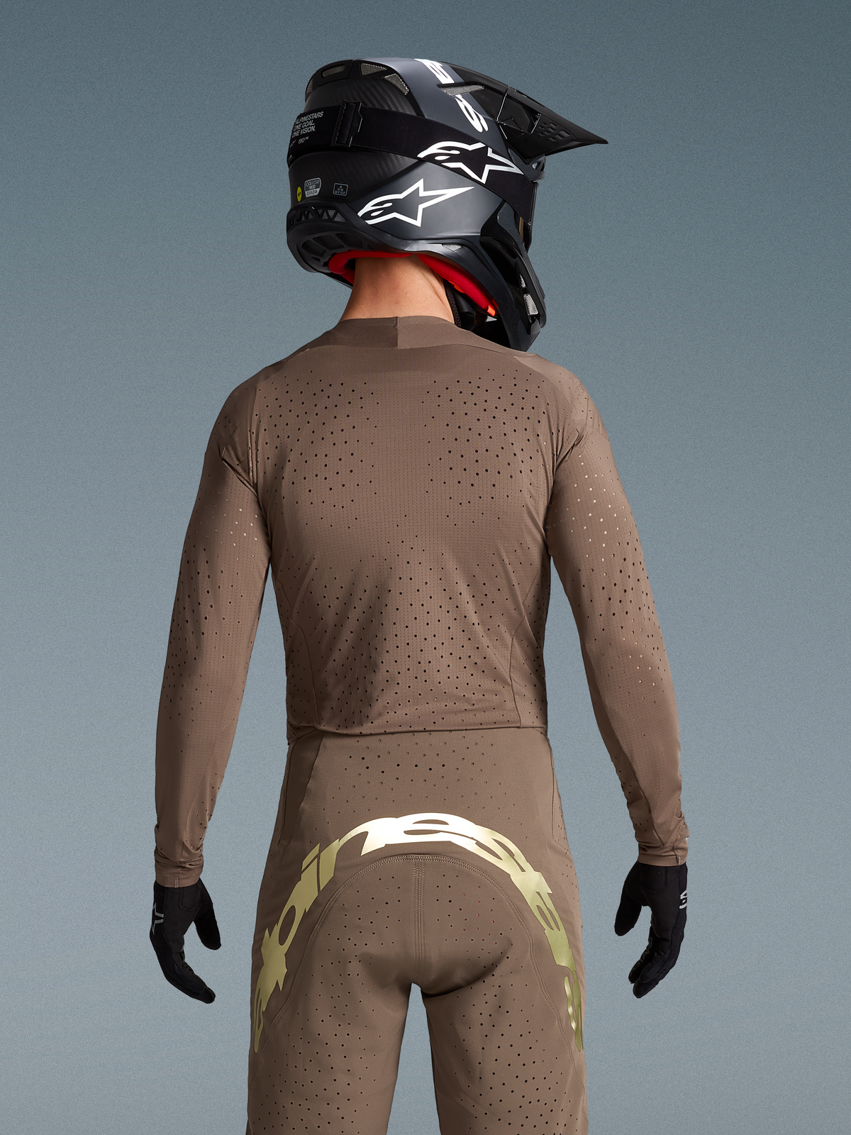 Alpinestars completo Supertech Air Gold edizione limitata, vista posteriore motocross marrone e oro con ventilazione laser.