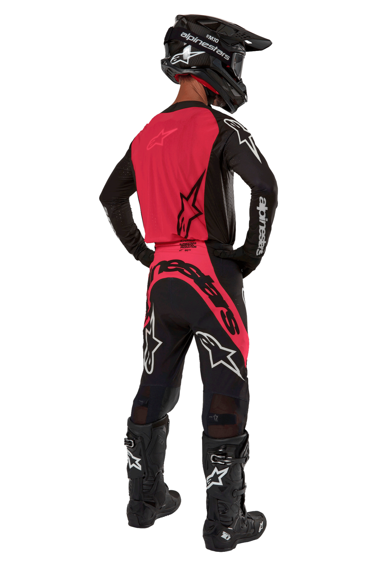Pilota di motocross visto da dietro che indossa la maglia Supertech Ward 2024 in Black Red Berry, con pannello posteriore rosso e maniche nere con marchio Alpinestars bianco, abbinata a pantaloni coordinati, stivali Tech 10 neri e casco in fibra di carbonio nero.