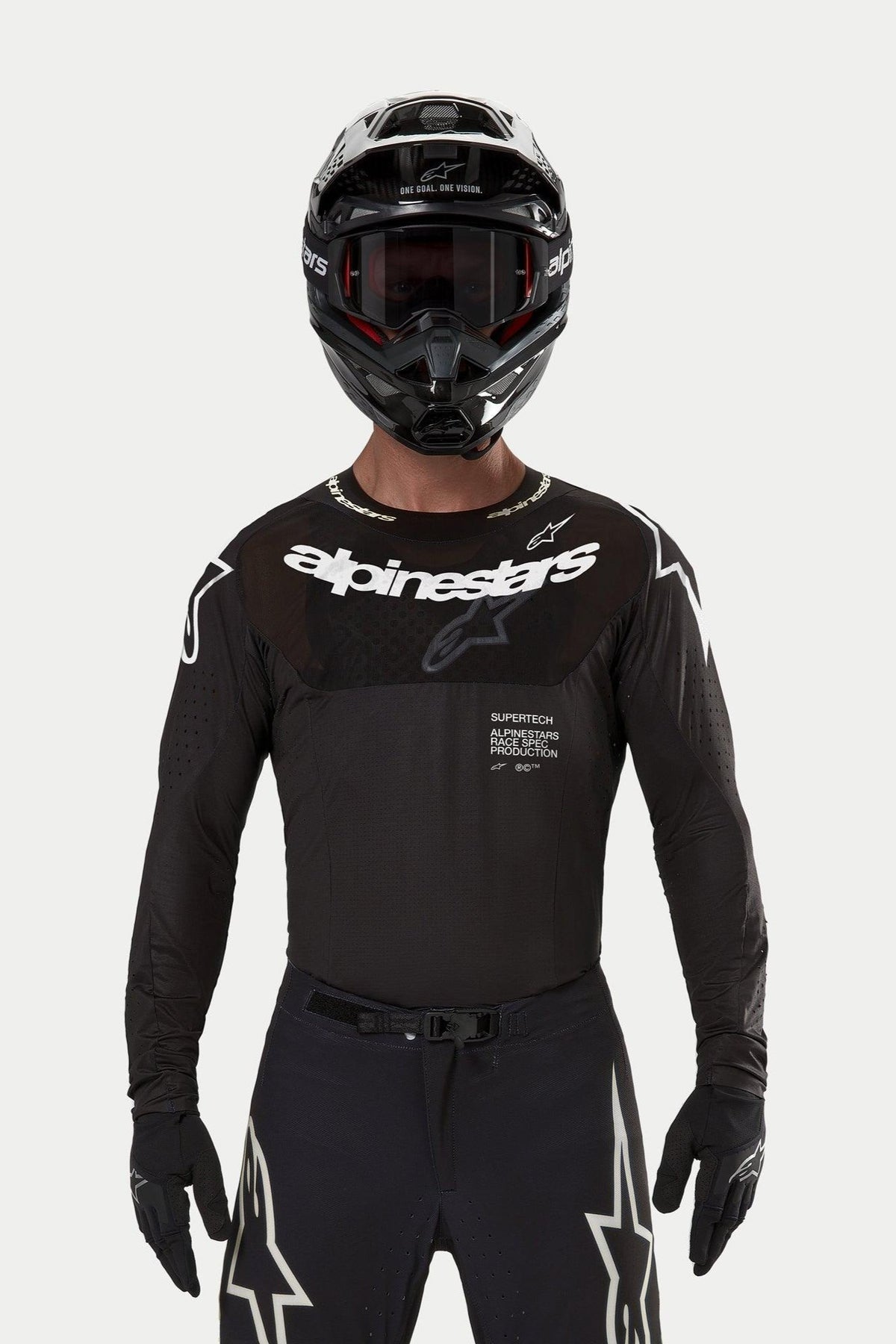 Pilota di motocross con maglia Alpinestars Supertech Ward 2024 in nero, vestibilità atletica da gara, logo Alpinestars bianco sul petto, perforazioni tagliate al laser e scritta 'Supertech Race Spec', abbinata a casco e occhiali neri per il fuoristrada.