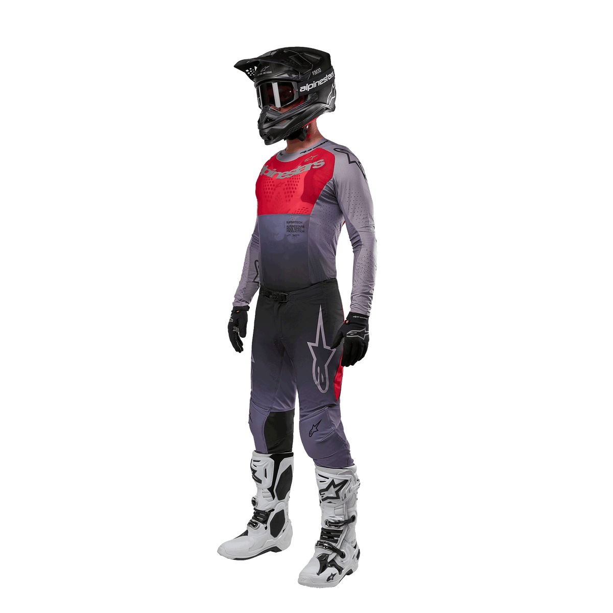 Pilota di motocross con abbigliamento completo da gara, maglia Alpinestars 2024 Supertech Dade in Iron Red Berry e grigio, pantaloni grigi coordinati con accenti rossi, casco nero con occhiali, stivali bianchi e neri, guanti neri, outfit coordinato per corse fuoristrada