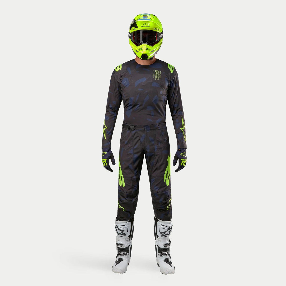 Pilota di motocross con equipaggiamento completo da gara, maglia Techstar Rantera 2024 in nero, navy e giallo fluo, pantaloni coordinati con stampa astratta, casco giallo fluo brillante, stivali bianchi e neri, outfit coordinato per corse off-road