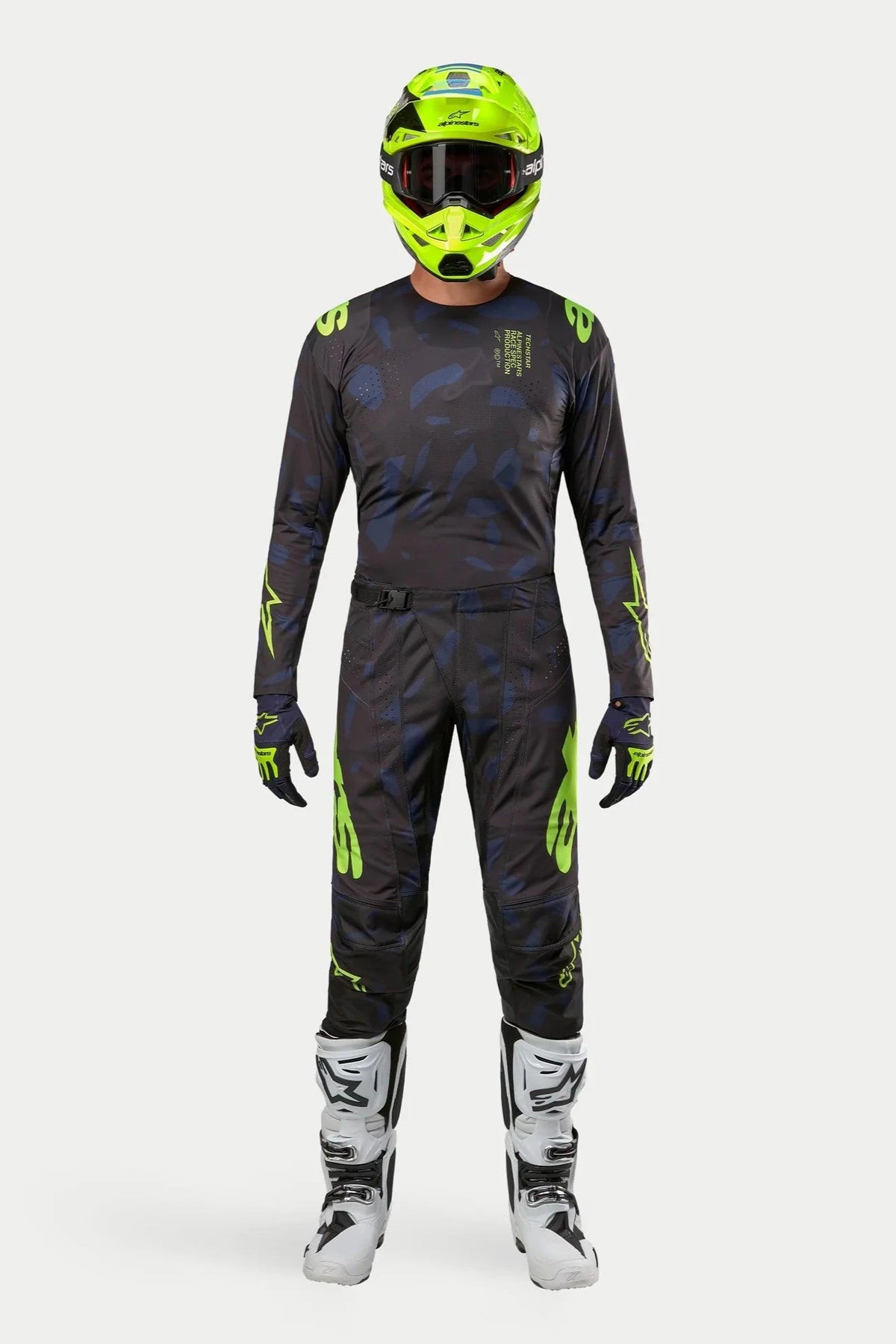 Alpinestars Techstar Rantera 2024, completo maglia e pantaloni da motocross, nero, blu navy e giallo fluo, indossato con casco giallo fluorescente coordinato e stivali bianchi, con branding giallo vivace e pannelli tecnici in mesh per prestazioni fuoristrada