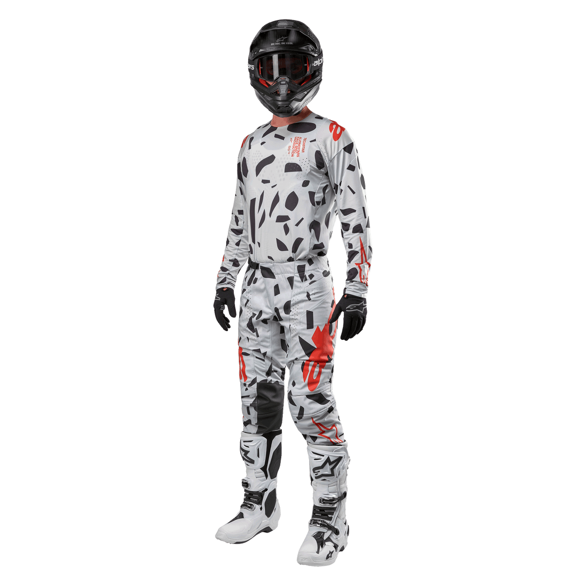 Pilota di motocross con maglia Alpinestars 2024 Techstar Rantera in Haze Gray Camo, pantaloni coordinati con accenti rossi e neri, casco e occhiali neri, guanti neri, stivali bianchi e neri, abbigliamento completo da motocross per prestazioni off-road
