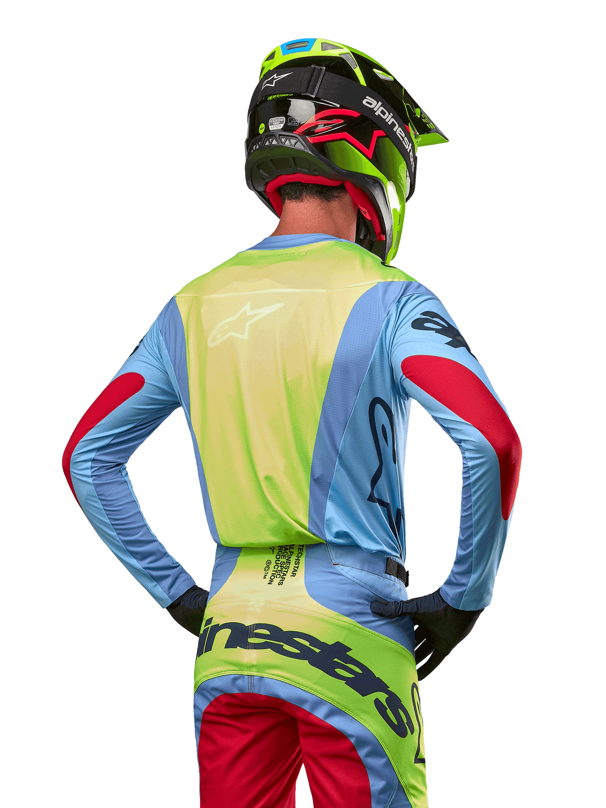 Pilota di motocross visto da dietro con maglia Alpinestars 2024 Techstar Ocuri, azzurro con retro giallo fluo e dettagli rossi sulle maniche, pantaloni da motocross coordinati e casco giallo neon, completo per gare fuoristrada