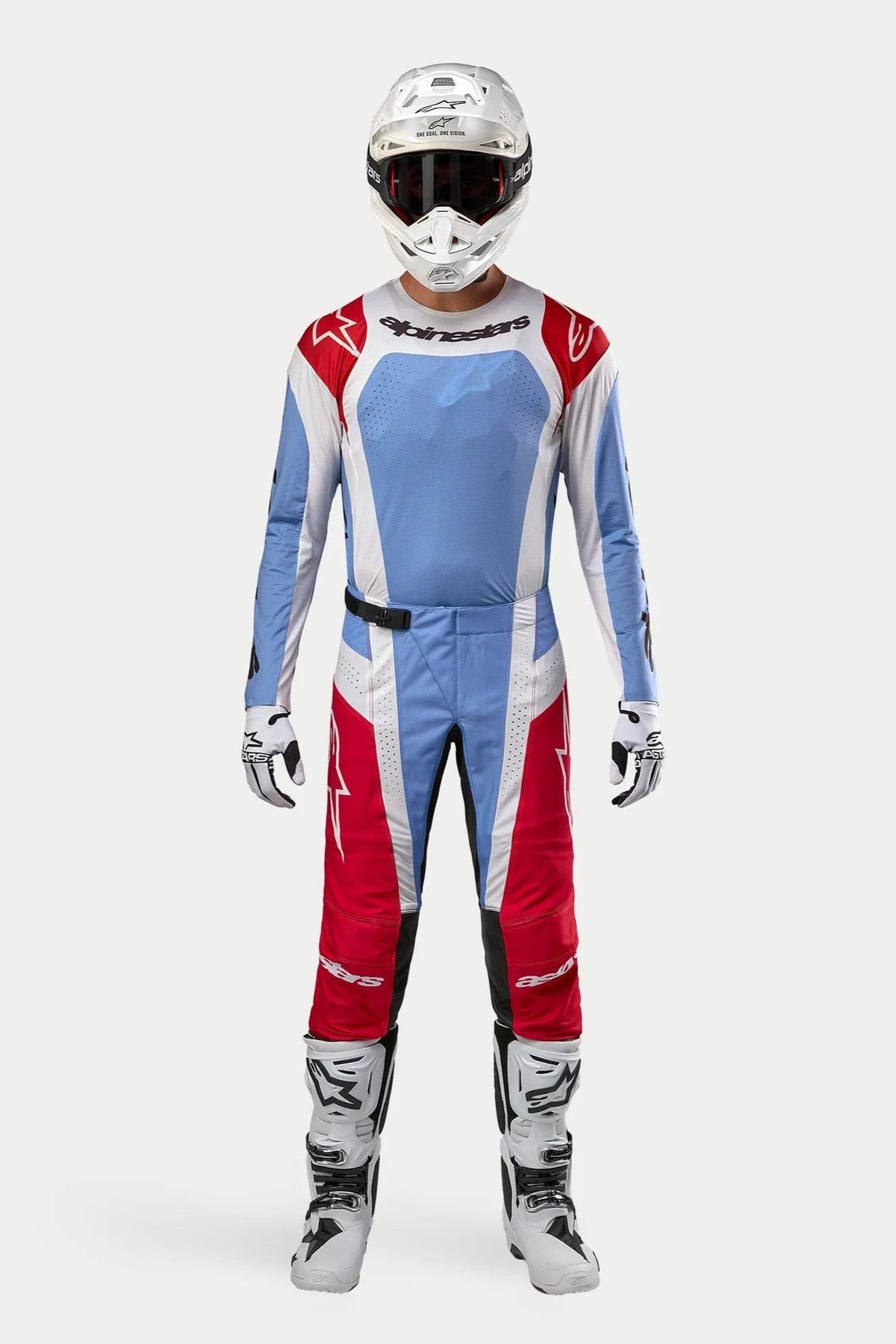 Pilota di motocross che indossa la maglia Techstar Ocuri 2024 in Light Blue Mars Red White, pantaloni da motocross coordinati, casco bianco con maschera e stivali bianchi, set completo di abbigliamento professionale da fuoristrada