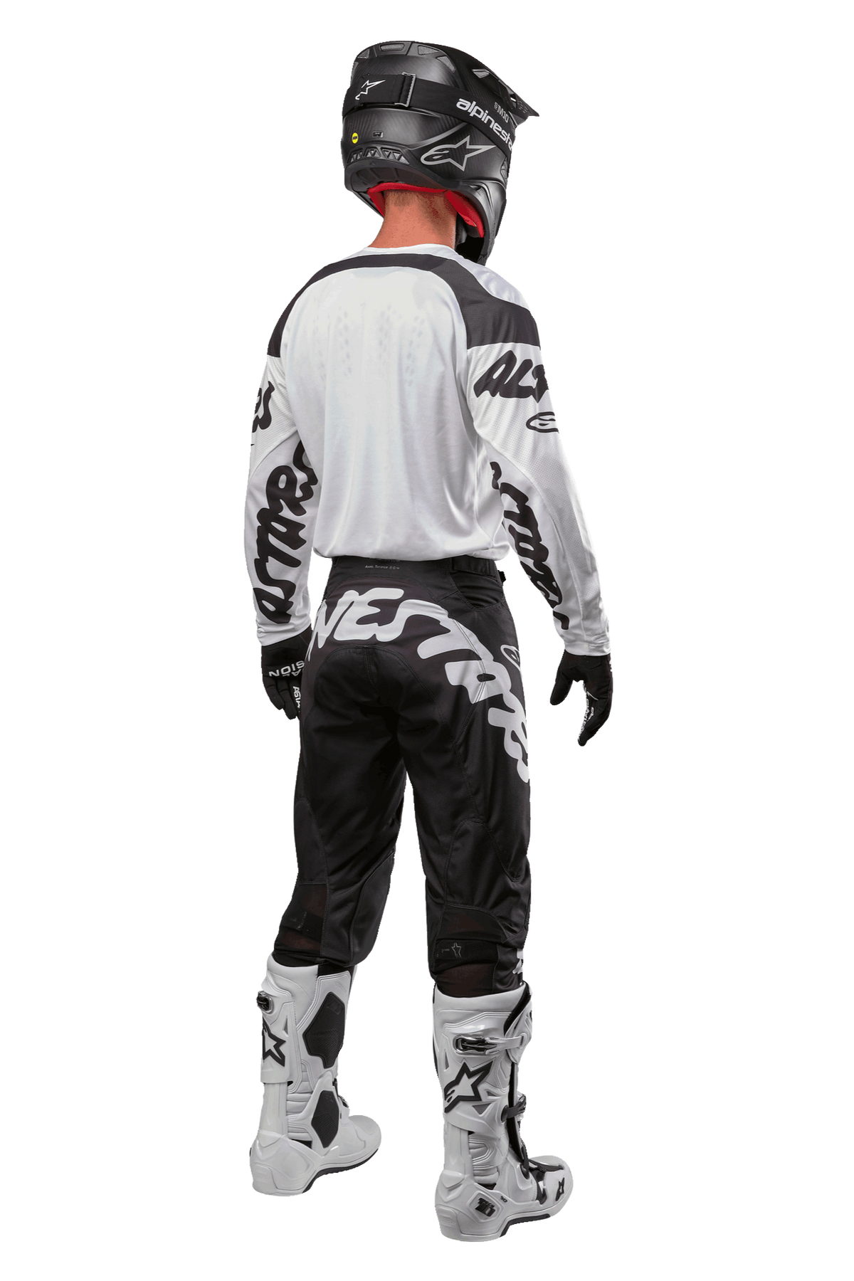 Alpinestars Racer Hana Jersey 2024, vista posteriore di un pilota di motocross, Bianco e Nero, maglia bianca con grafiche nere sulle maniche, abbinata a pantaloni neri con scritta Alpinestars bianca sulla seduta, casco nero e stivali bianchi e neri, equipaggiamento coordinato da corsa fuoristrada