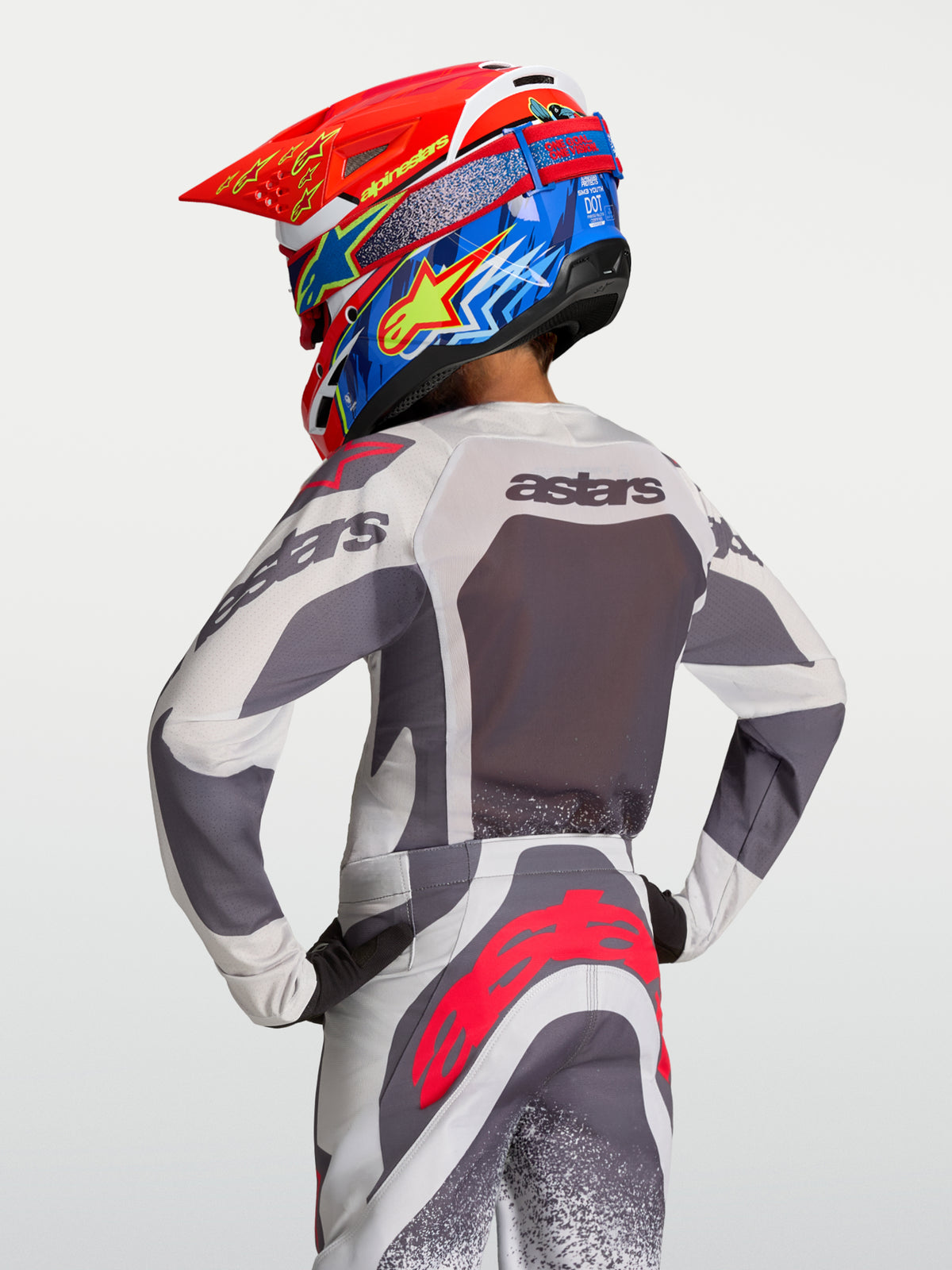 Alpinestars maglia Supertech Swan ragazzo 2027, maglia motocross grigia e lilla in mesh, vista posteriore su pilota.