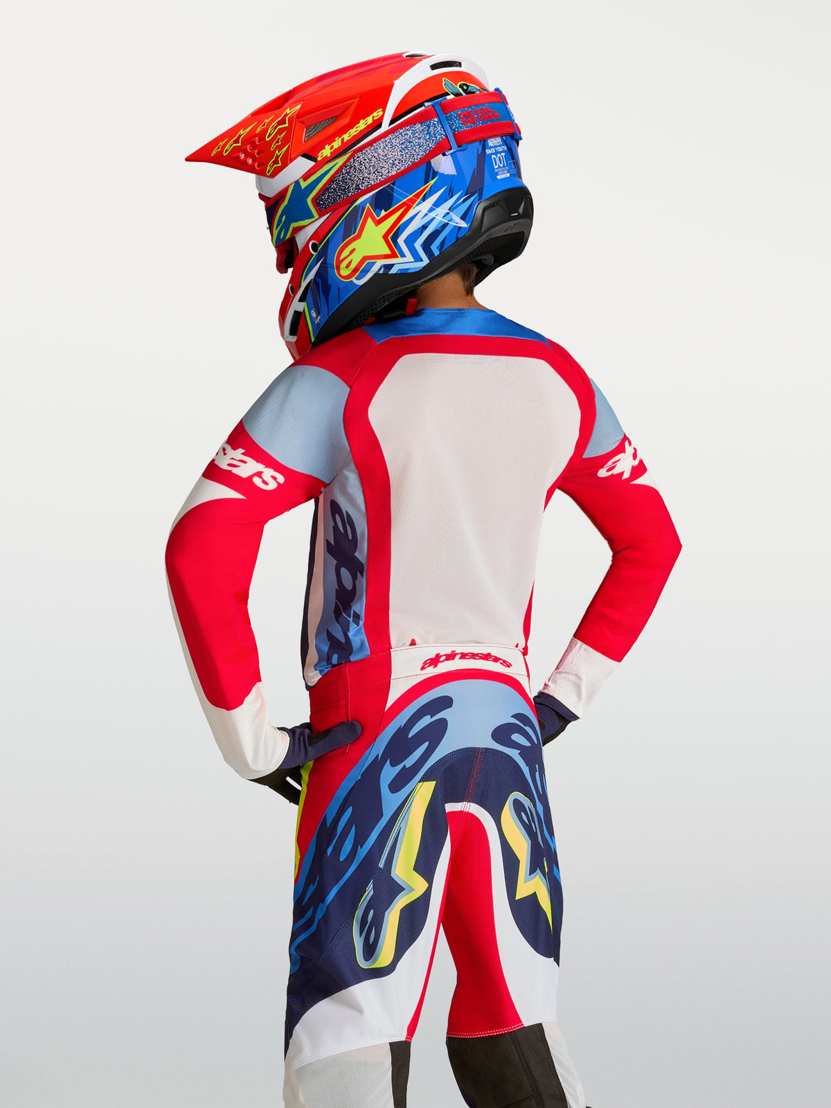Alpinestars Maglia Supertech Dyna Ragazzo 2027, maglia motocross rossa e blu navy, mesh traspirante, vista posteriore su pilota.