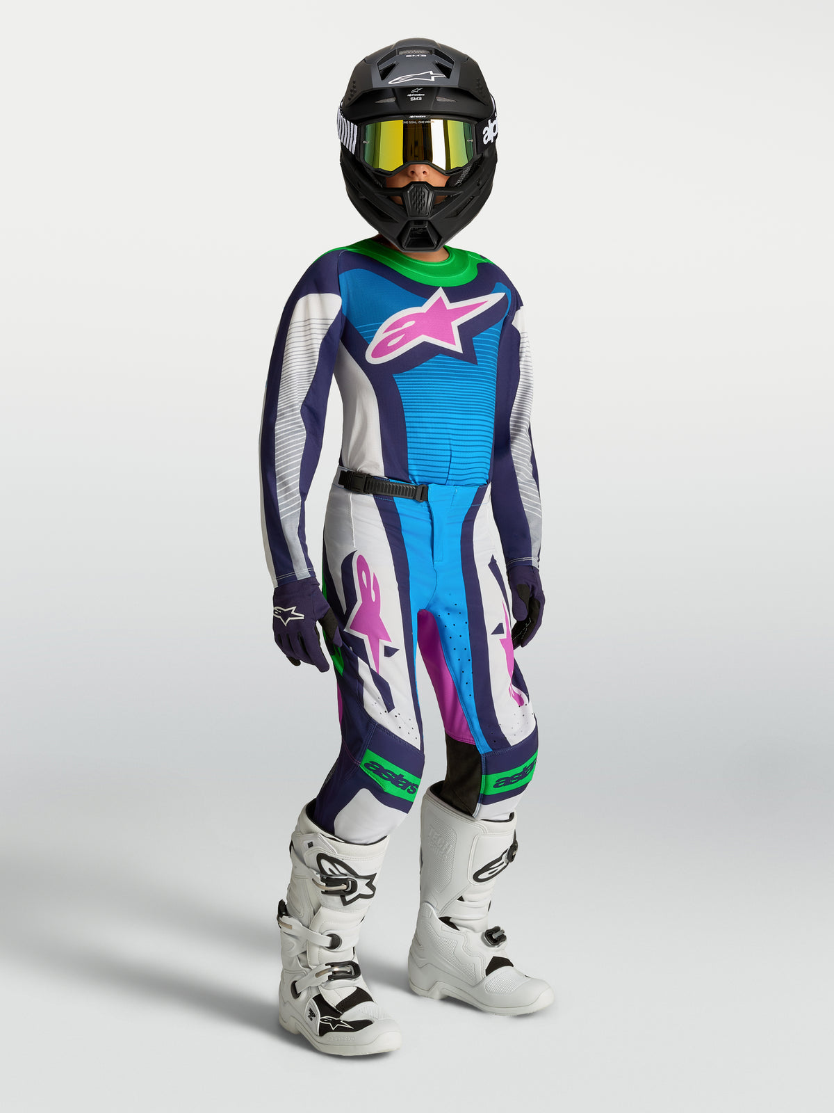 Alpinestars completo Supertech Maven ragazzo 2027, maglia e pantaloni motocross bianchi e blu con dettagli verdi e stivali.