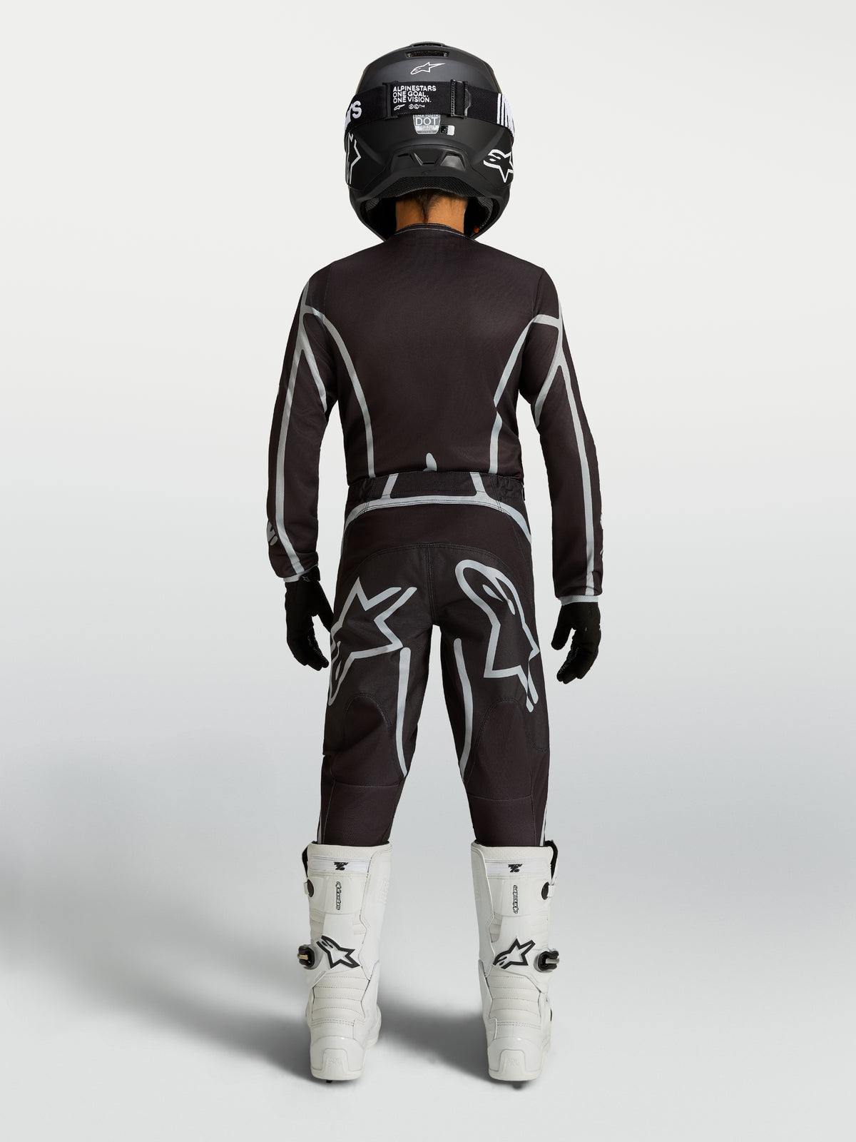 Alpinestars Ragazzo Fluid Apex V2 Gear Set e maglia, completo motocross nero e argento con stivali bianchi, vista posteriore