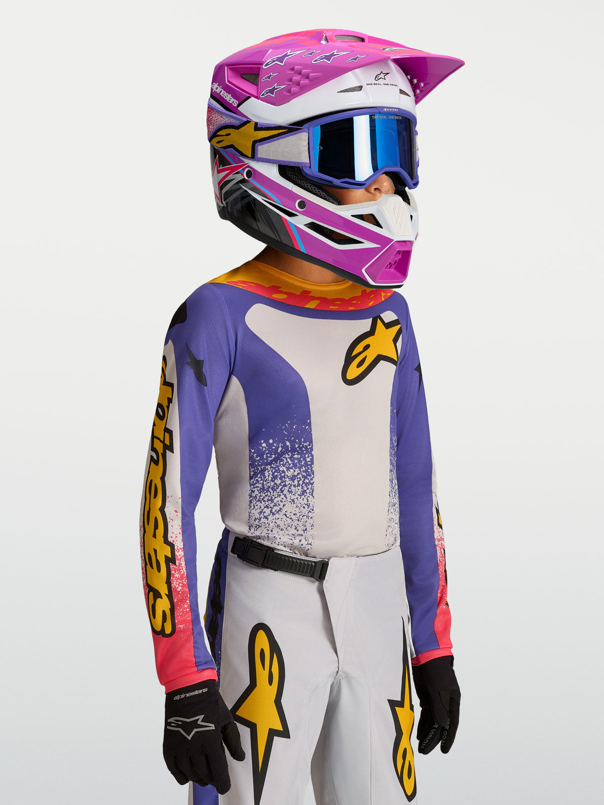 Alpinestars Maglia Fluid Drag Ragazzo 2027, maglia da motocross per ragazzi, blu e bianca con accenti gialli, indossata da un giovane pilota con casco coordinato, abbigliamento tecnico per off-road