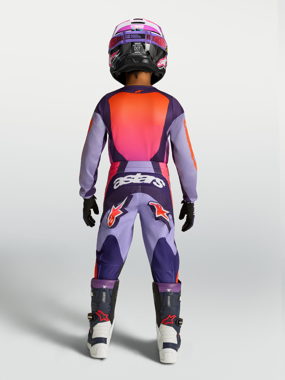 Alpinestars maglia e gear set Fluid Hunt ragazzo 2027, completo motocross viola e rosa fluo, vista posteriore pilota ragazzo.