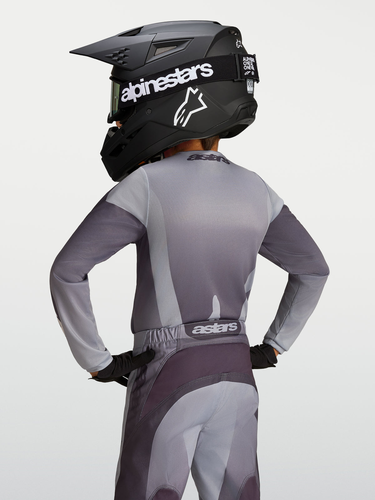 Alpinestars Maglia Fluid Amber Ragazzo, maglia da motocross in poliestere grigia e sabbia, vista posteriore su giovane pilota.