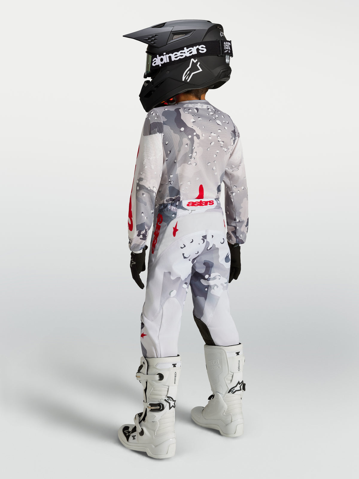 Alpinestars ragazzo Fluid Lone gear set 2027, completo motocross grigio camo e bianco con accenti rossi, vista posteriore.