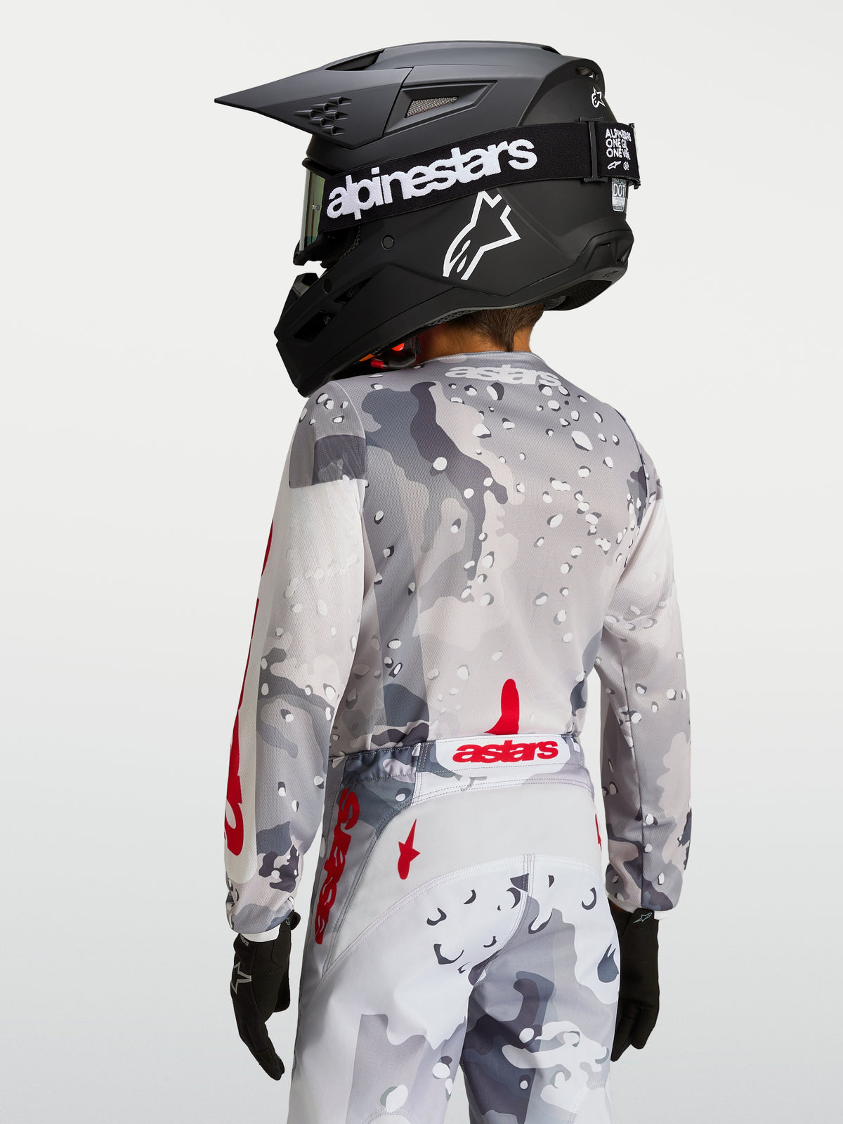 Alpinestars Maglia Fluid Lone Ragazzo, maglia da motocross per ragazzi, grigio camo e rosso, vista posteriore con orlo allungato e vestibilità ergonomica.
