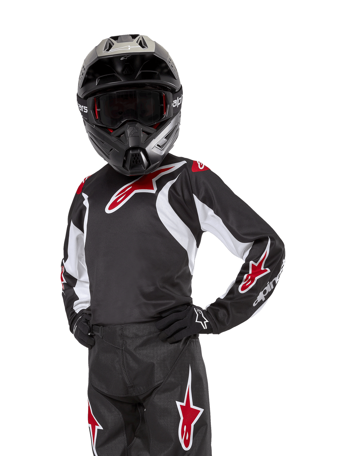 Alpinestars Youth 2024 Racer Lucent Jersey, maglia da motocross, nero bianco e rosso, indossata da un giovane pilota con casco nero e pantaloni coordinati, con loghi a stella rossi e accenti grafici bianchi, abbigliamento performance off-road per gare di motocross