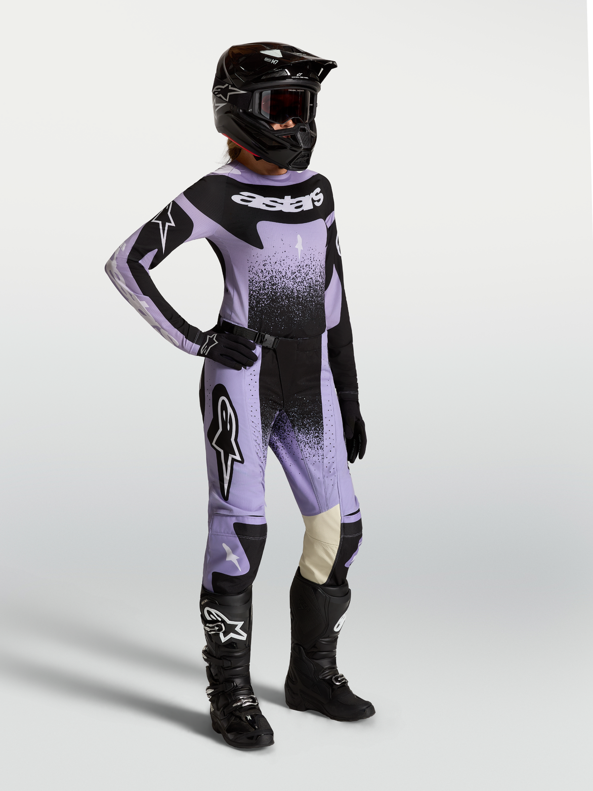 Alpinestars Stella Techstar Swan, completo motocross donna viola e nero con grafiche cigno, indossato con casco e stivali.
