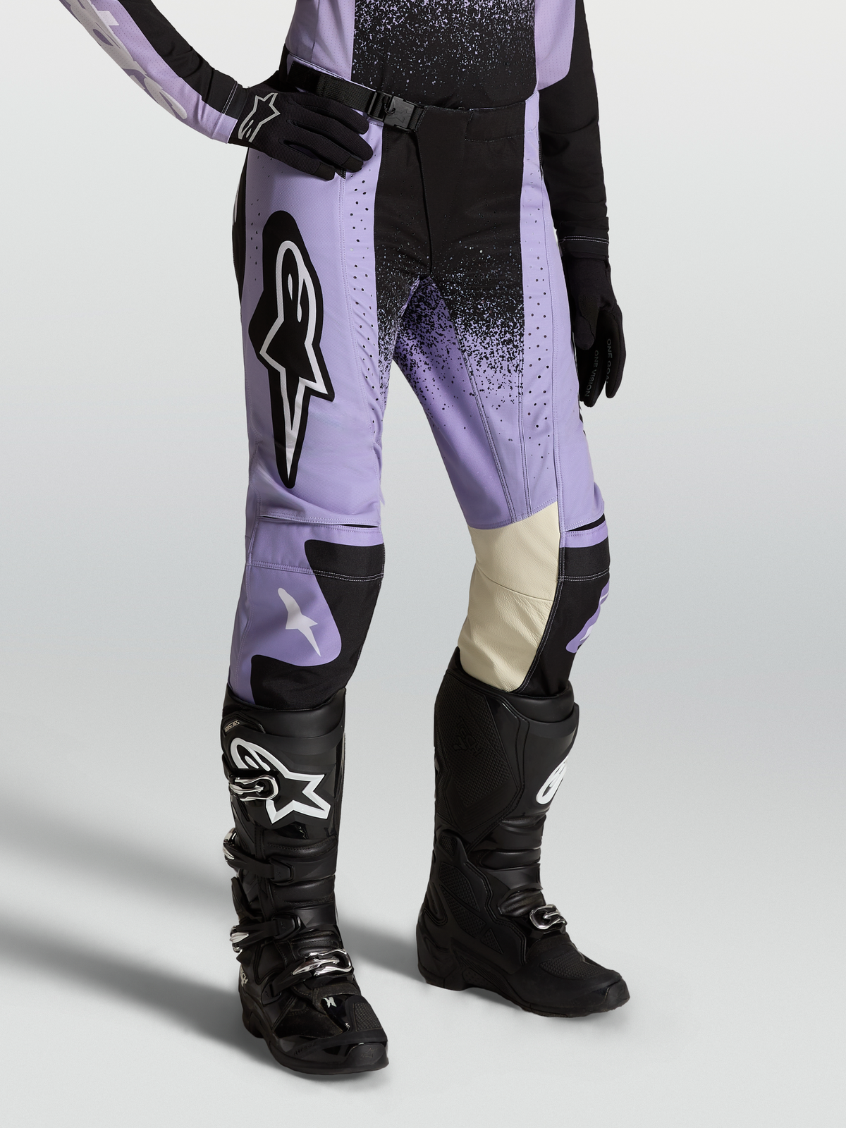 Alpinestars Pantaloni Stella Techstar Swan, pantaloni da motocross per donna, viola e nero, pannelli ginocchio in pelle bianca, indossati con stivali neri, abbigliamento fuoristrada premium