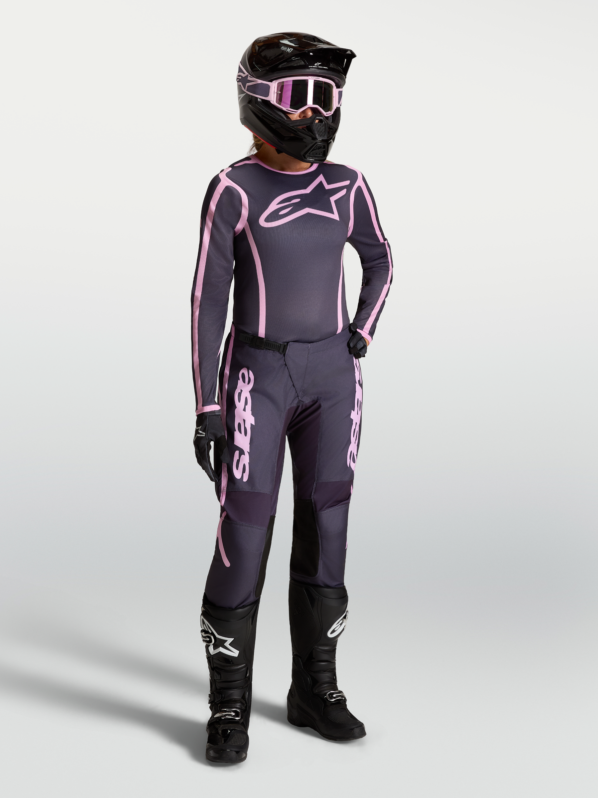 Maglia e completo Alpinestars Stella Fluid Apex V2, outfit da motocross da donna grigio e rosa con stivali da gara neri.